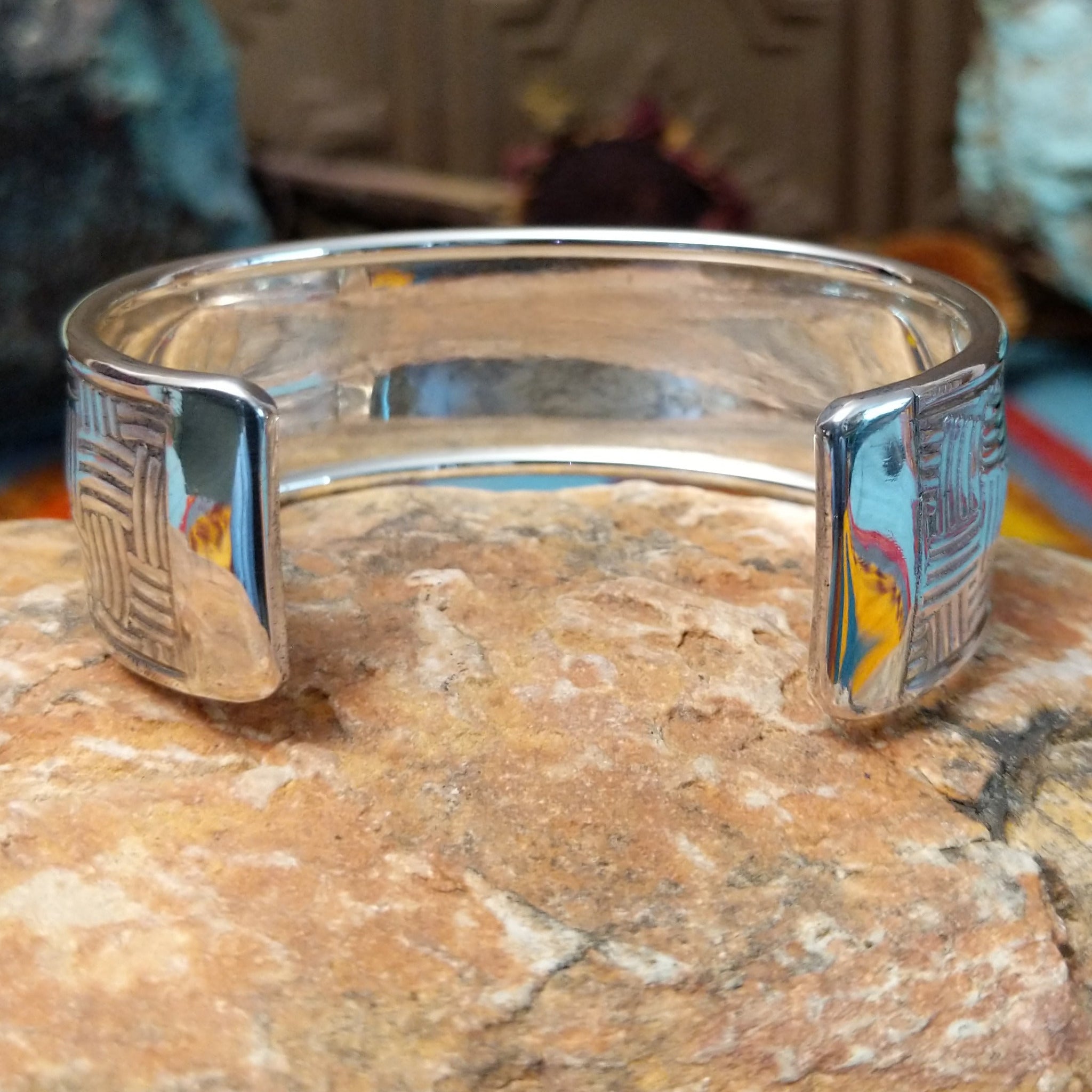 Wide silver cuff by Larry Joe with repeating curved line stampwork arranged in a woven pattern.