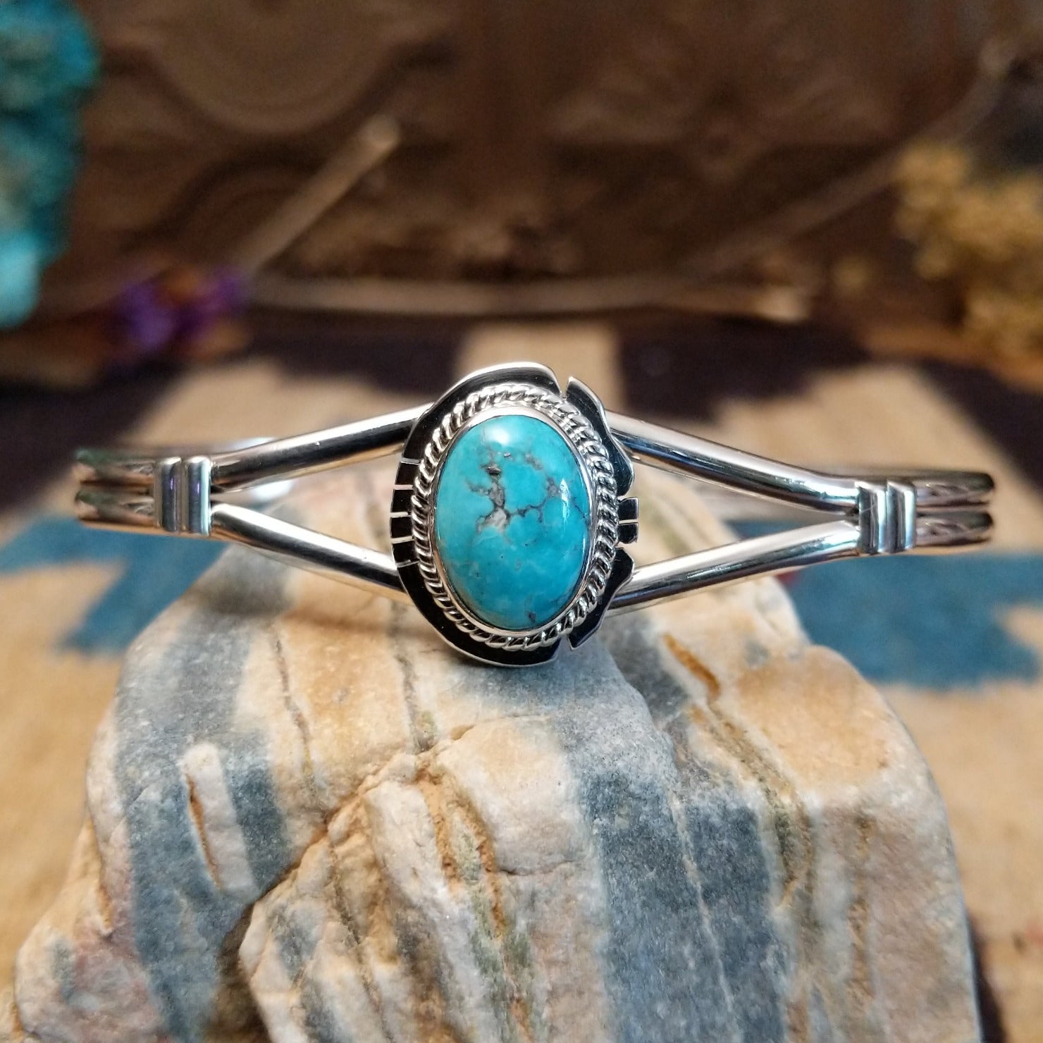 Sterling silver cuff with turquoise set in a round bezel, framed by twisted rope and an incised setting.