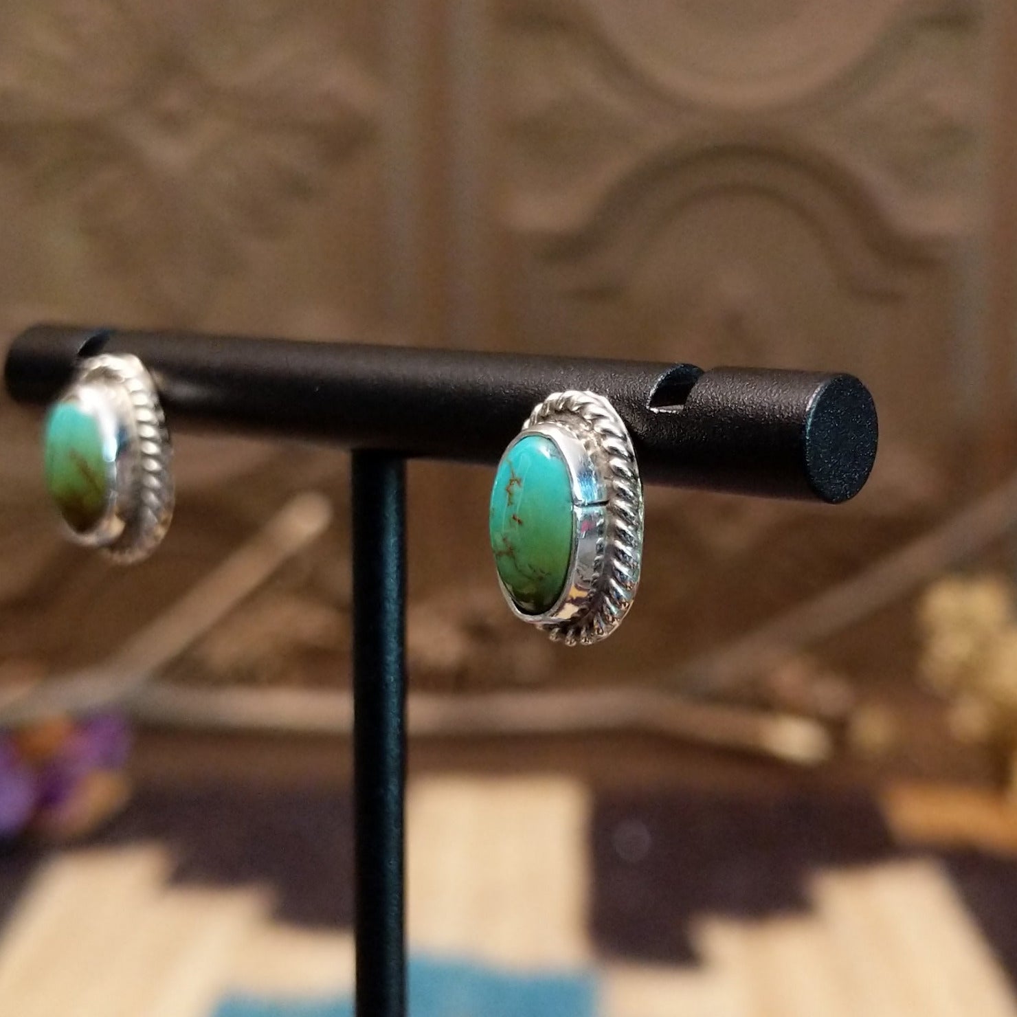 Sterling silver earrings with turquoise set in oval bezels, framed by twisted rope accents.