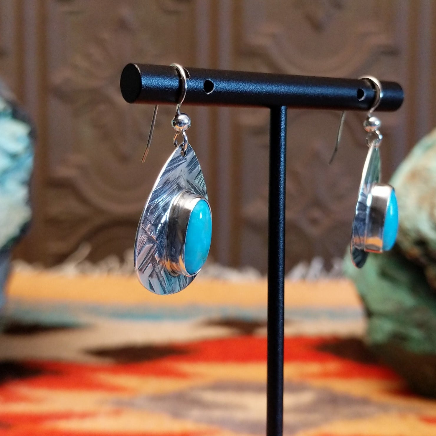 Sterling silver earrings with turquoise set in the oval bezels that are framed by the planished settings.