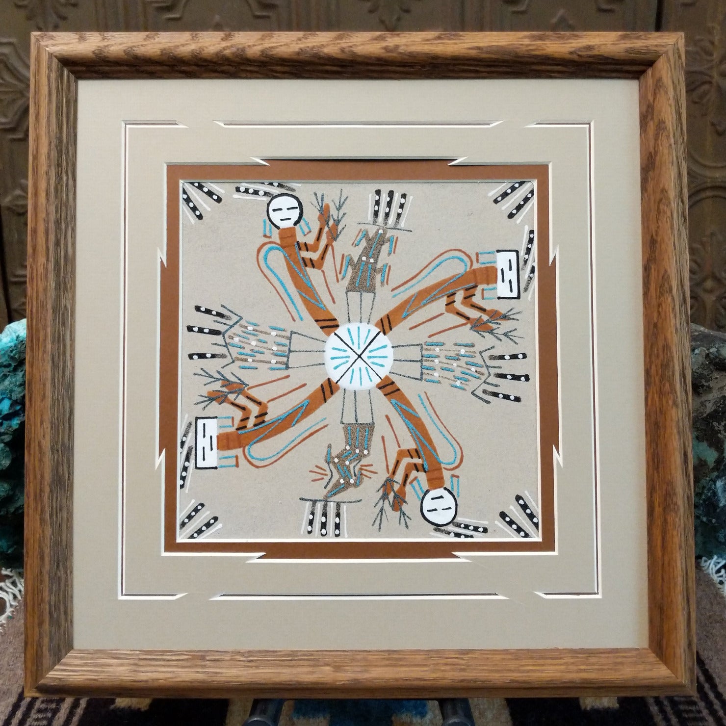 Framed Navajo sand painting of Rainbow People in a circular design.