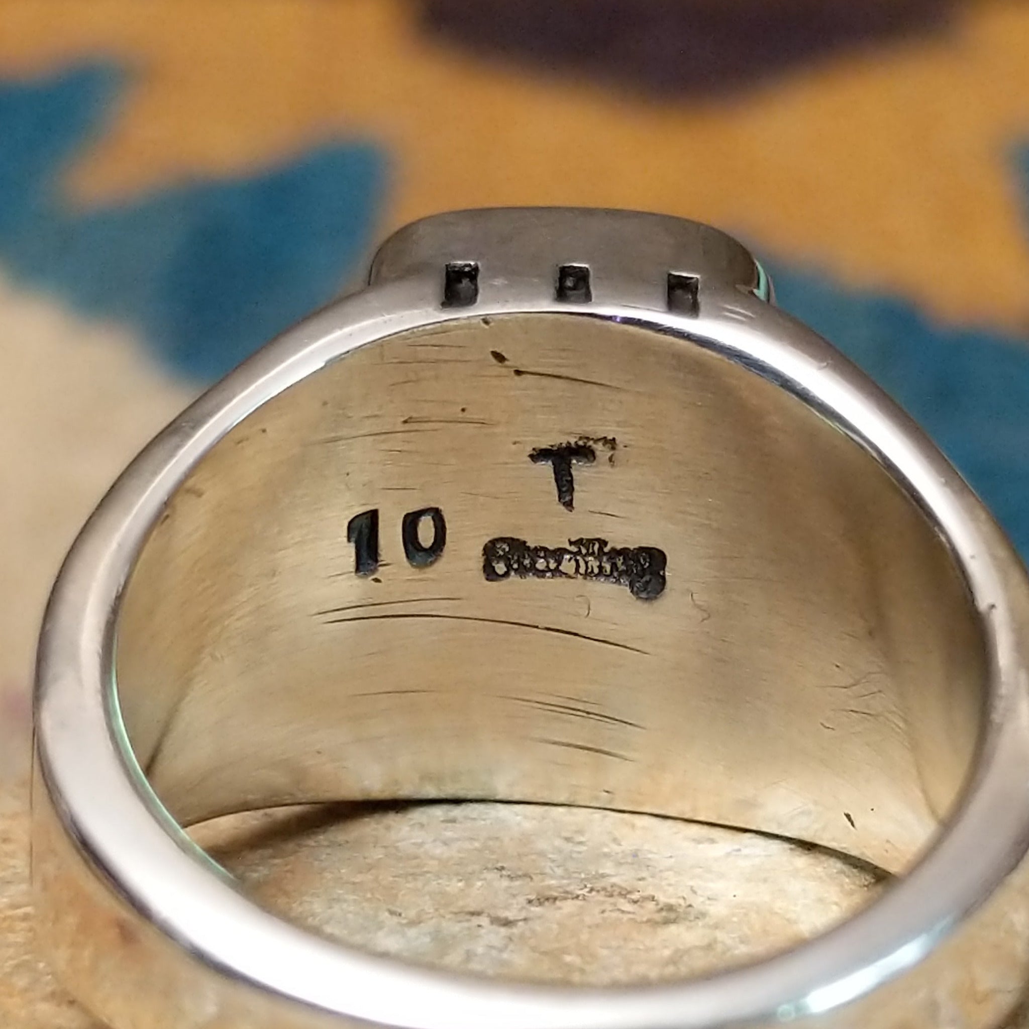 Handcrafted Navajo sterling silver ring by Terry Wood featuring a raised rectangular charoite cabochon with natural purple swirling patterns, set in a polished silver bezel with geometric detailing on the band; artisan and Sterling Silver stamp.