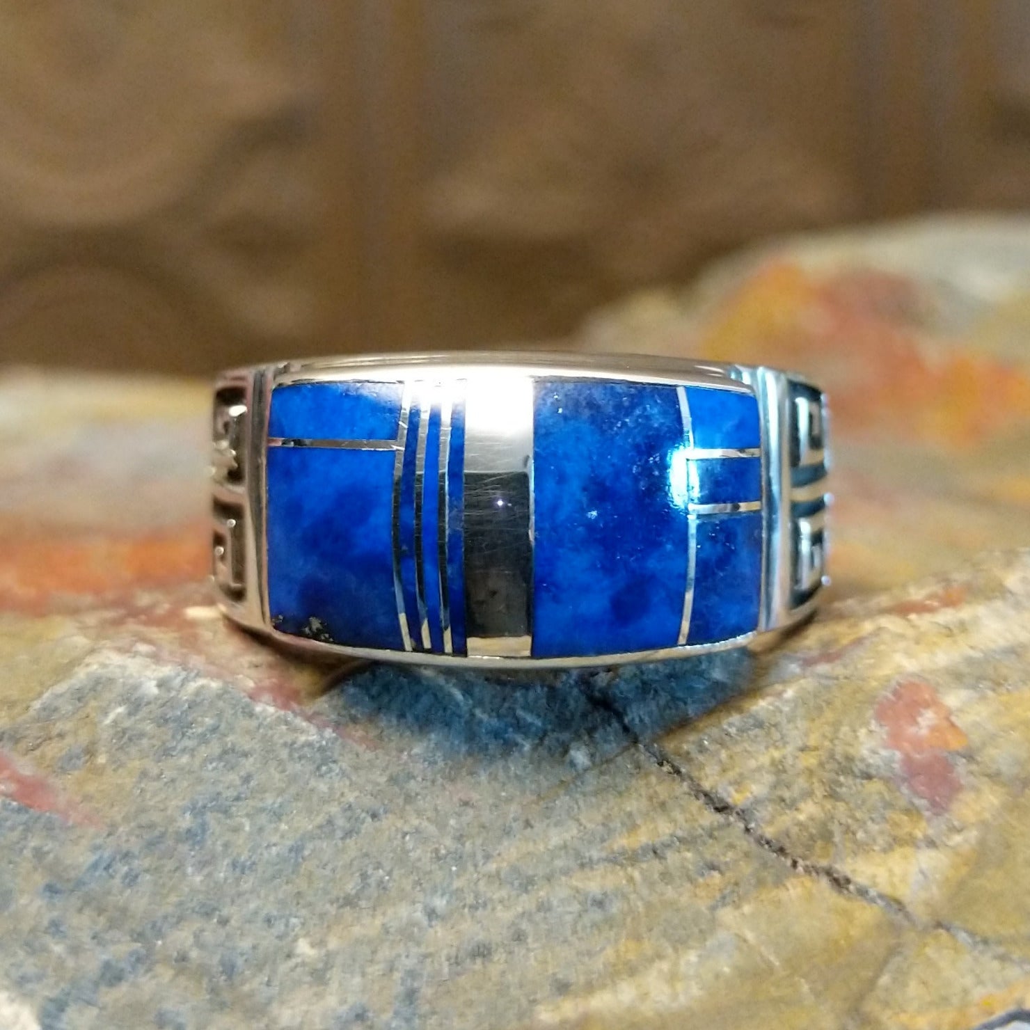 Sterling silver ring with lapis inlaid on the raised bezel and geometric designs on the band.