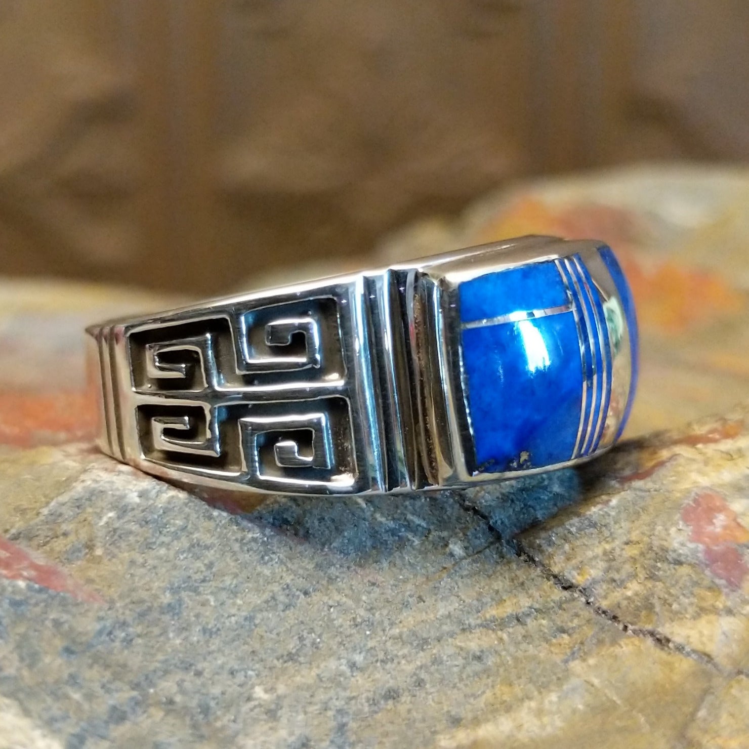 Sterling silver ring with lapis inlaid on the raised bezel and geometric designs on the band.