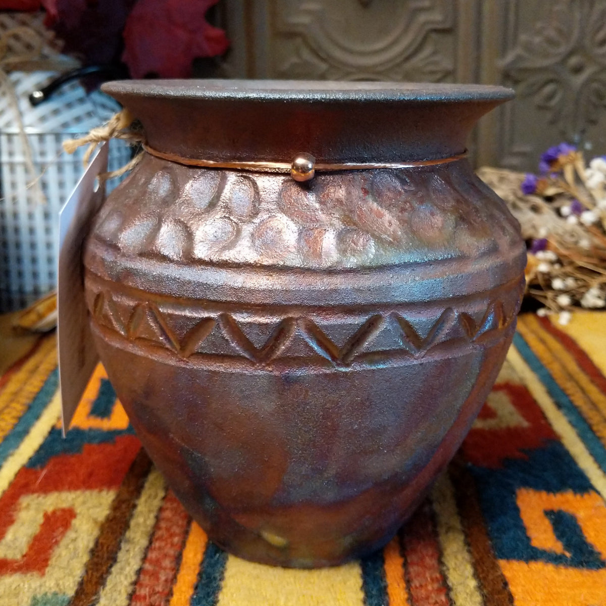 Round raku pottery vase by Roger Calhoun with a flared rim, raised geometric bands, and a metallic copper, bronze, and smoky brown finish.