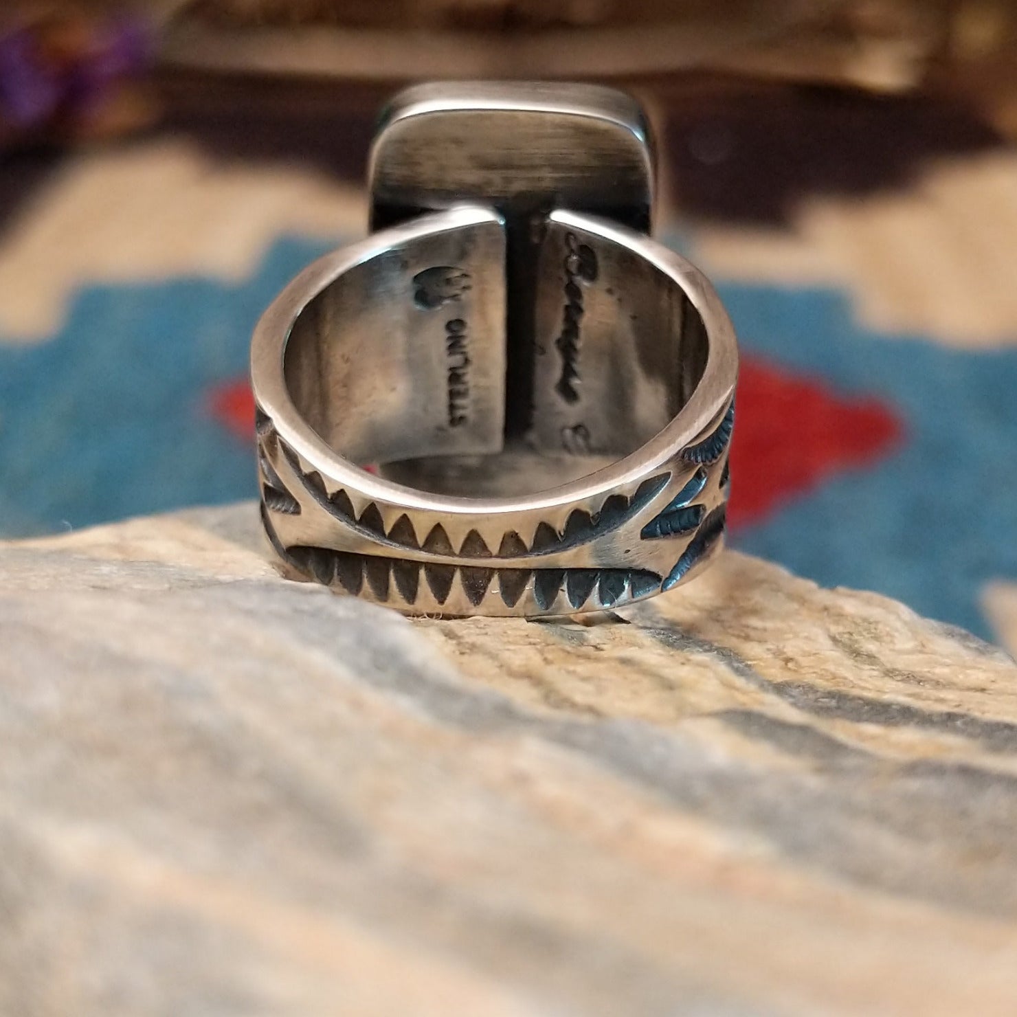 Sterling silver ring with white buffalo stone set in a rectangular bezel and stamped designs on the band.