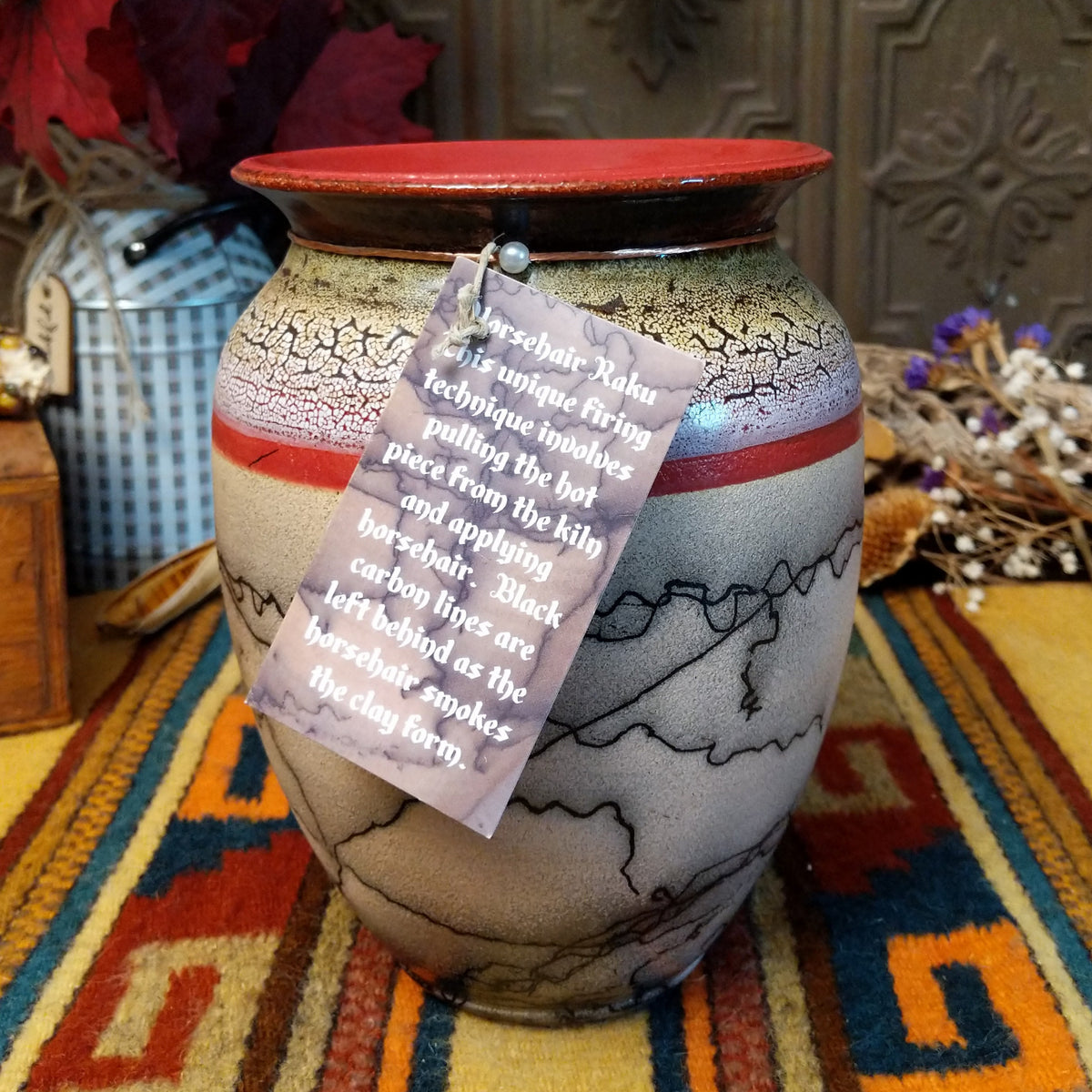 Rounded horsehair pottery vase by Roger Calhoun with a wide red rim, multicolored crackled shoulder, red accent band, and black horsehair markings across a cream-colored body.