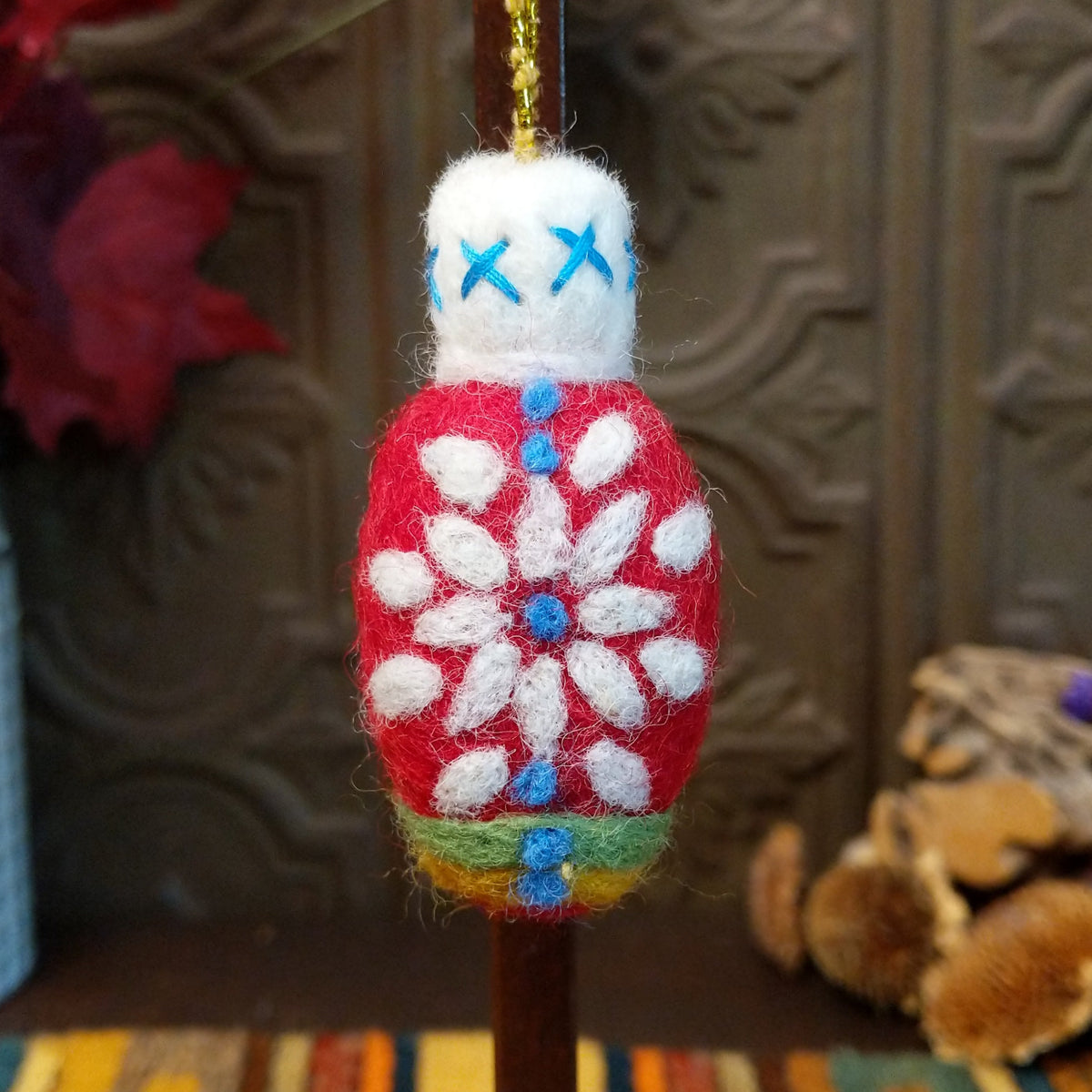This charming Red Snowflake Bulb Wool Ornament by Ganz features a bright red wool body with a white snowflake design, blue accents, green and yellow bands near the bottom, a fluffy white top with blue stitching, and a gold hanging cord.