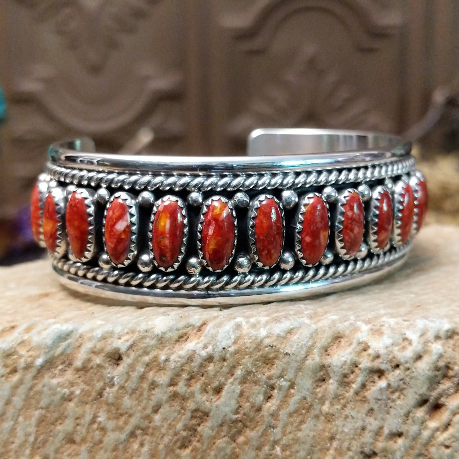 Sterling silver cuff bracelet with red spiny oyster shell set in oval bezels, lined along the surface and twisted rope with dotted accents.