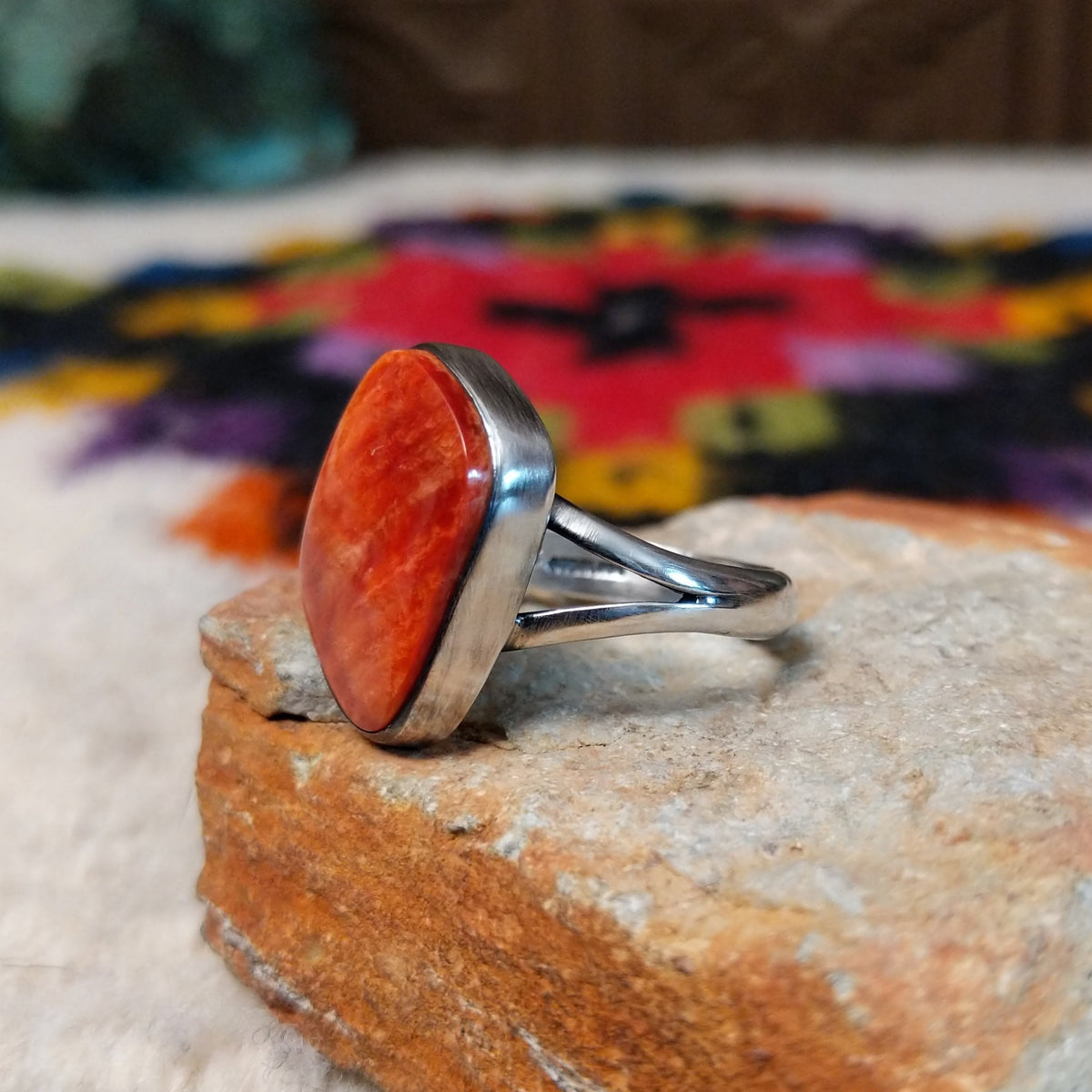 Red spiny oyster shell ring by Bernyse Chavez with an irregular polished stone and split silver band.