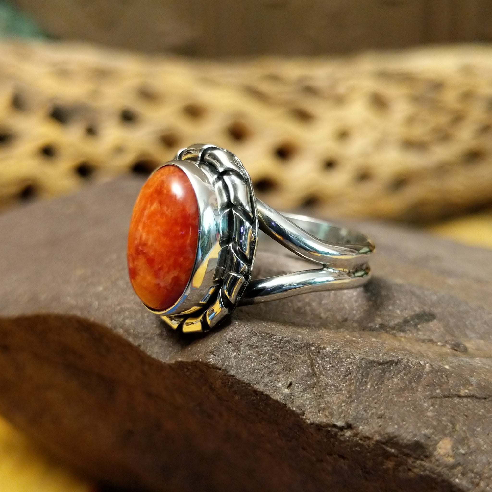 Red spiny oyster shell ring by Terry Wood, featuring a vibrant red spiny oyster shell set in a handcrafted sterling silver band with traditional Southwestern-inspired metalwork. Side view.
