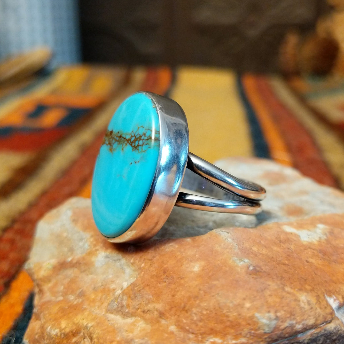 Redskin Turquoise Ring by Everett & Mary Teller featuring a large oval sky-blue turquoise stone with distinctive brown spiderweb matrix, a smooth polished surface, and a simple silver bezel setting; side view.