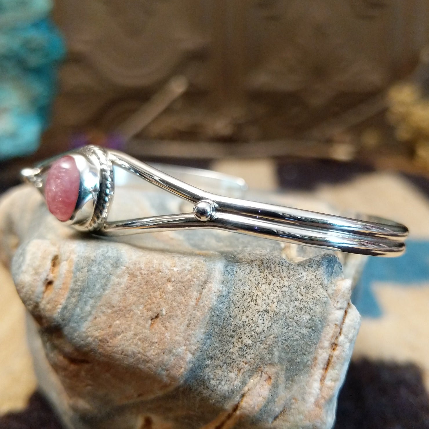 Sterling silver cuff with rhodochrosite set in a round bezel, framed by twisted rope accents.