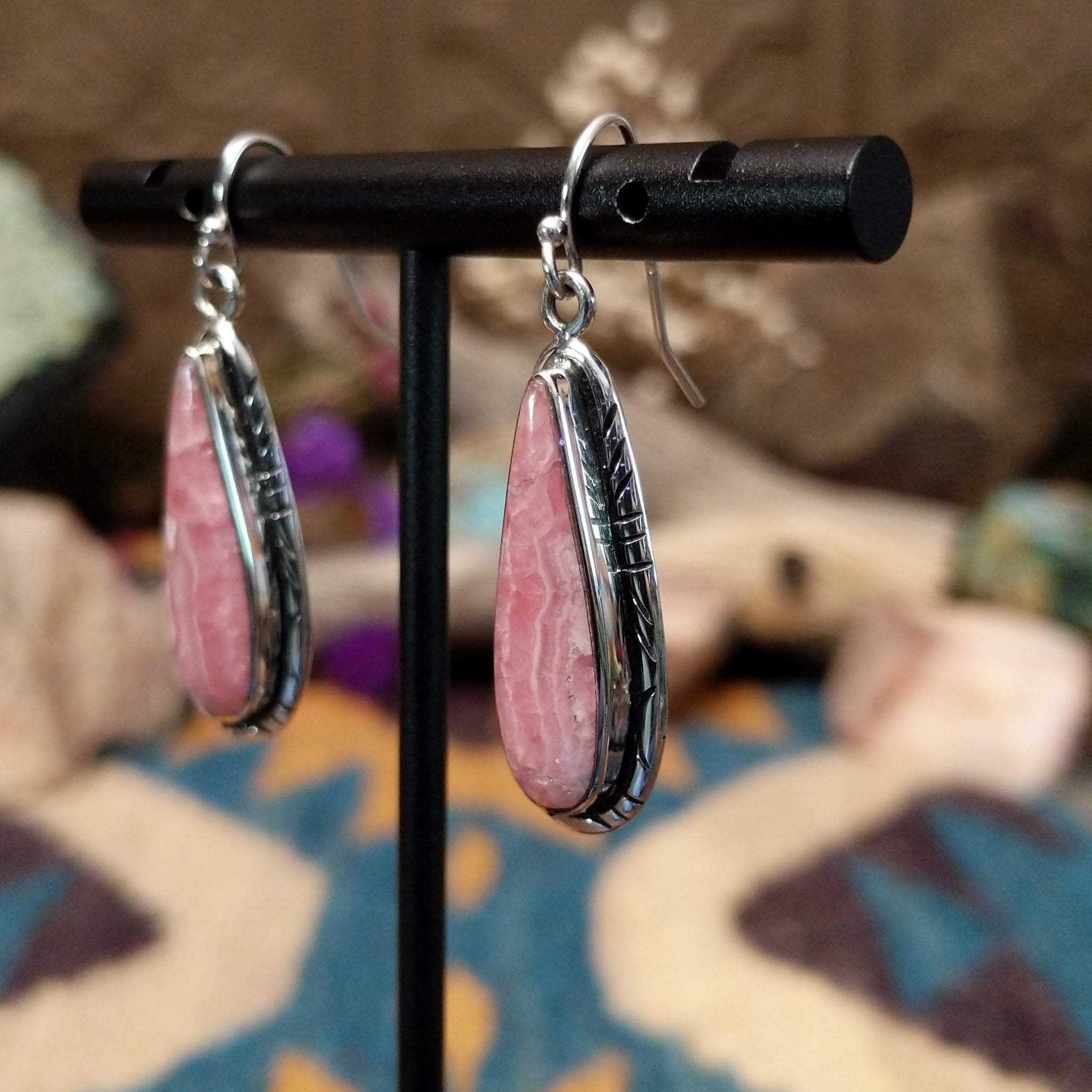 Handcrafted sterling silver teardrop earrings by John King featuring natural rhodochrosite with soft pink and white banding in hand-stamped sterling silver settings on French hooks; side view.