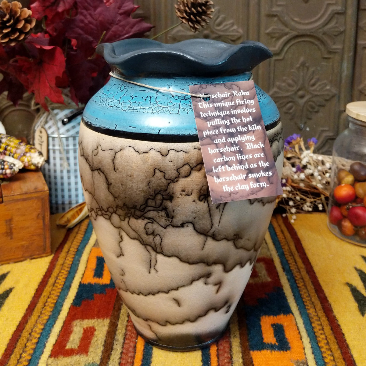 Horsehair pottery vase by Roger Calhoun with a rippled dark rim, metallic blue crackled upper section, and branching black horsehair patterns across a cream-colored body.