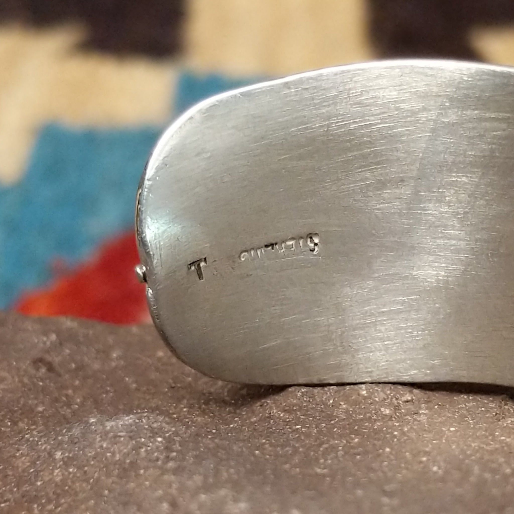 Rippling silver feather cuff by Terry Wood, featuring a handcrafted sterling silver feather design with flowing engraved details and traditional Southwestern-inspired craftsmanship. Artisan and Sterling Silver stamp.
