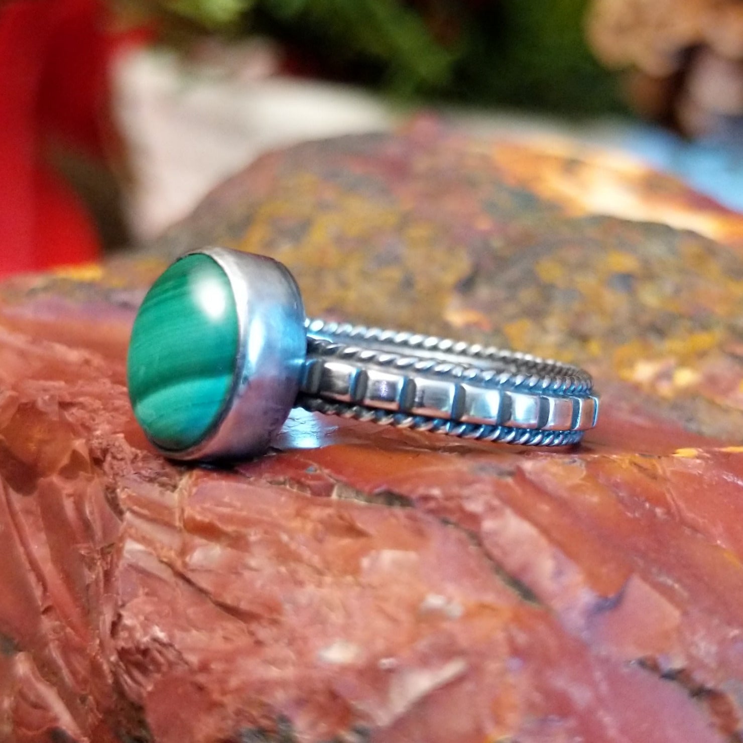 Sterling silver ring with patterned band, twisted rope accents, and malachite set in the round bezel.