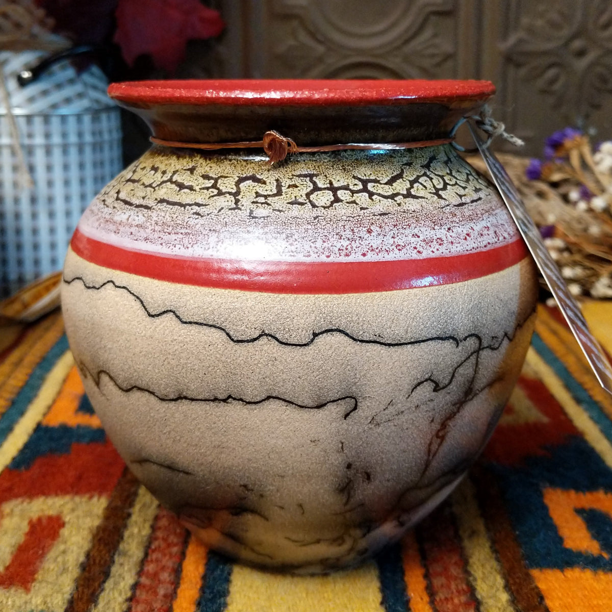 Round horsehair pottery vase by Roger Calhoun with a wide red rim, gold and lavender crackled shoulder, red accent band, and smoky black horsehair markings across a cream-colored body.