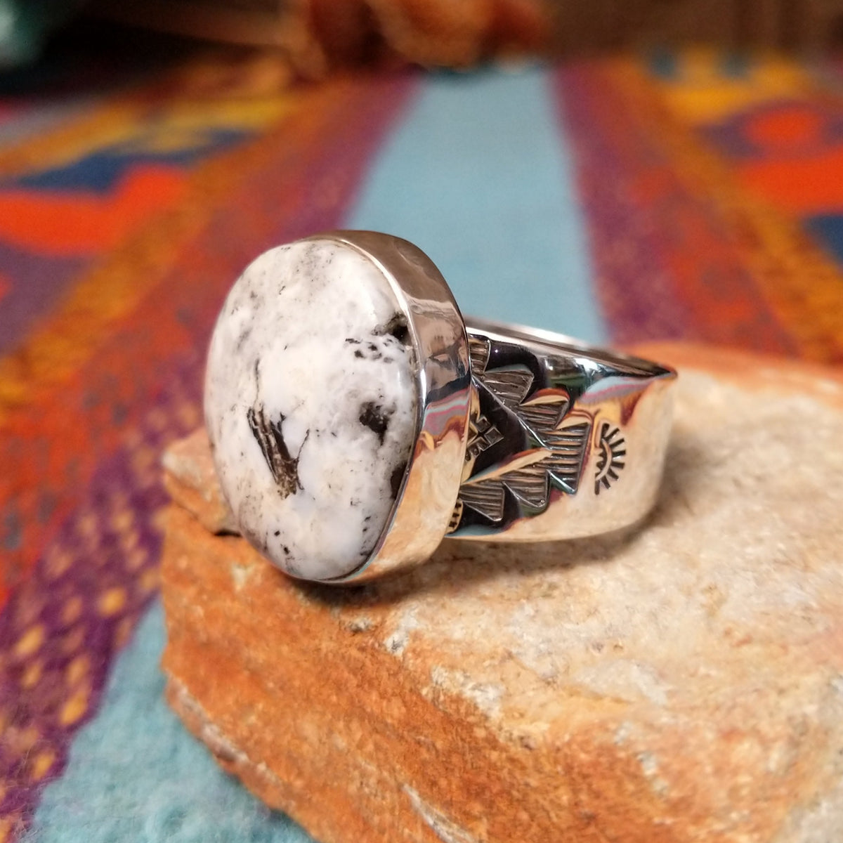 Round White Buffalo Ring by L.P. featuring a large creamy white cabochon with natural black and gray matrix, set in a smooth silver bezel with a substantial detailed silver band; side view.
