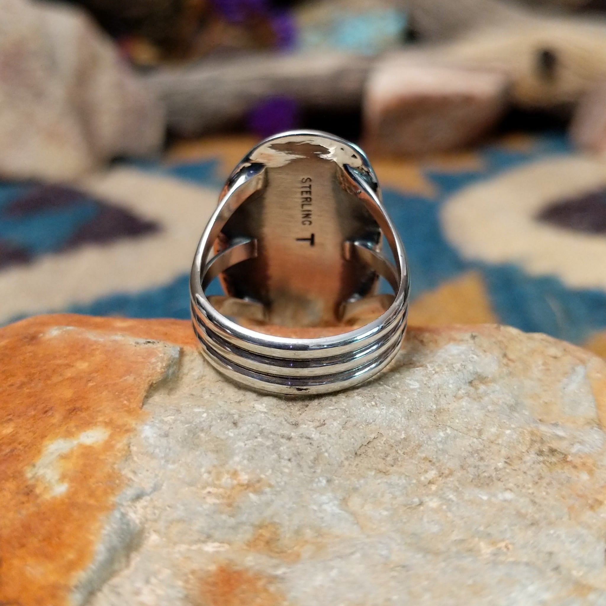 Handcrafted sterling silver ring featuring an elongated oval Royston turquoise cabochon with vivid green tones and golden-brown matrix, set in an ornate oxidized silver bezel with decorative bead accents; underside view.