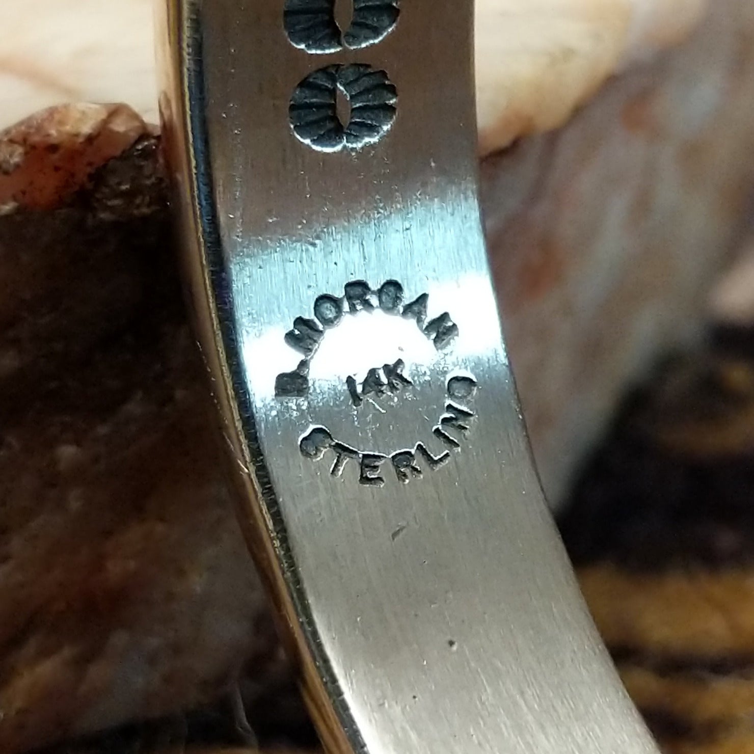 Close up of artist's stamped signature and stamped 14K and Sterling, indicating 14 karat gold and sterling silver construction.