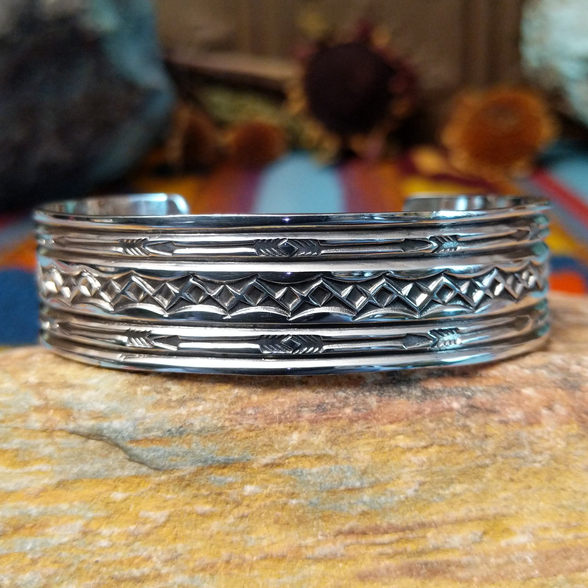 Silver cuff by Sunshine Reeves with two stamped arrows and central repeating diamond pattern.
