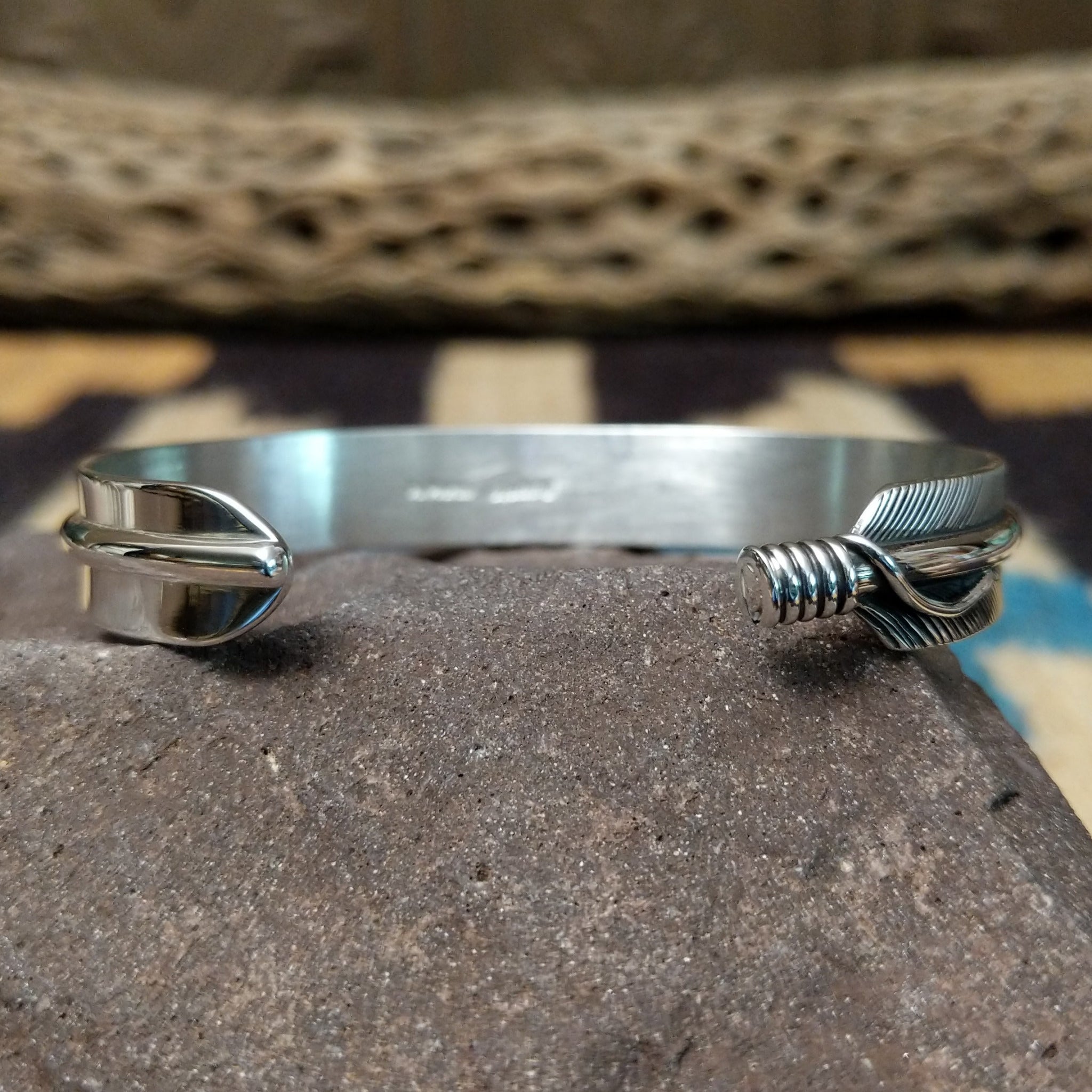 Silver feather cuff by Angela Martin, featuring a handcrafted sterling silver feather design with engraved details and traditional Southwestern craftsmanship. Underside view.