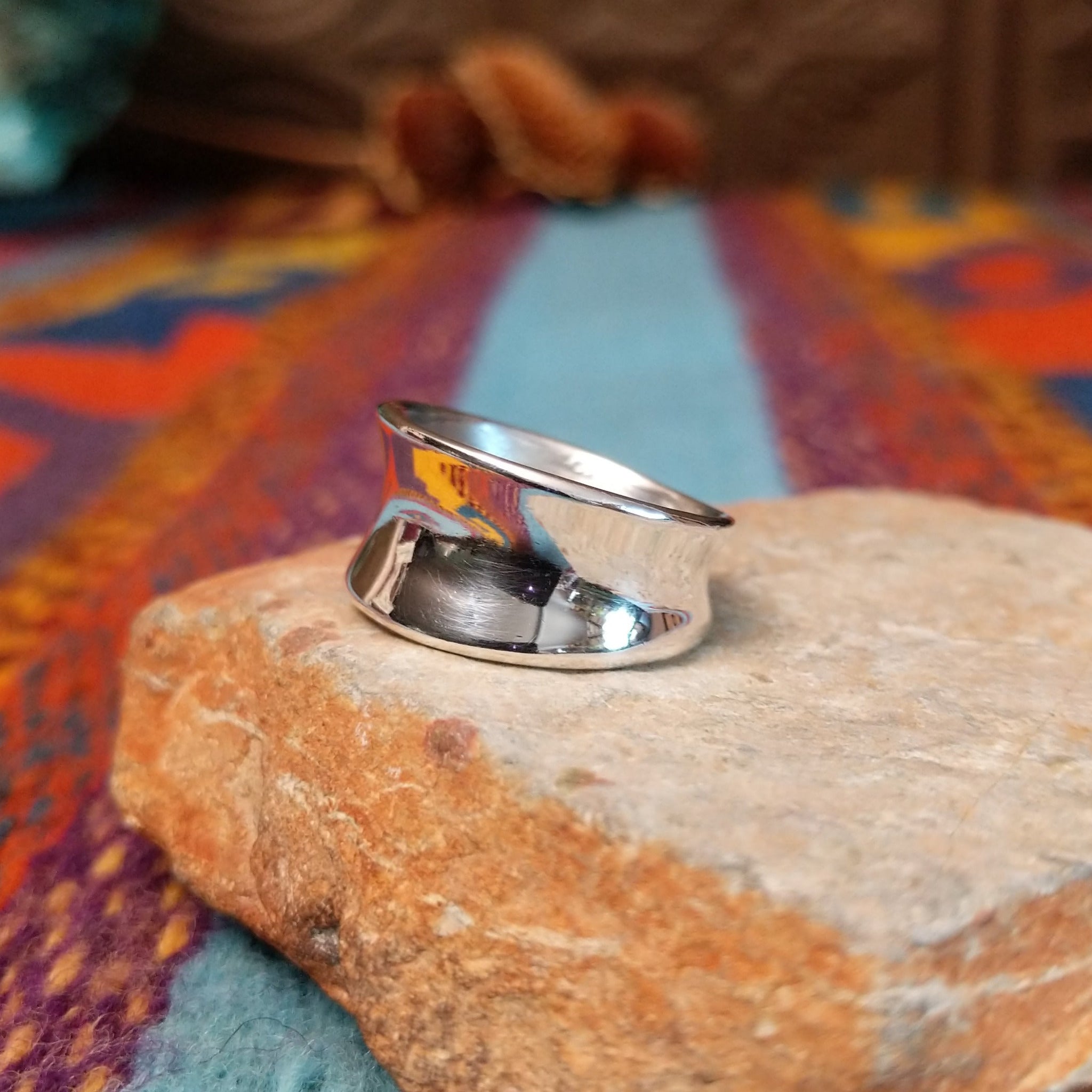Polished silver saddle ring by Raymond Coriz with broad curved face.