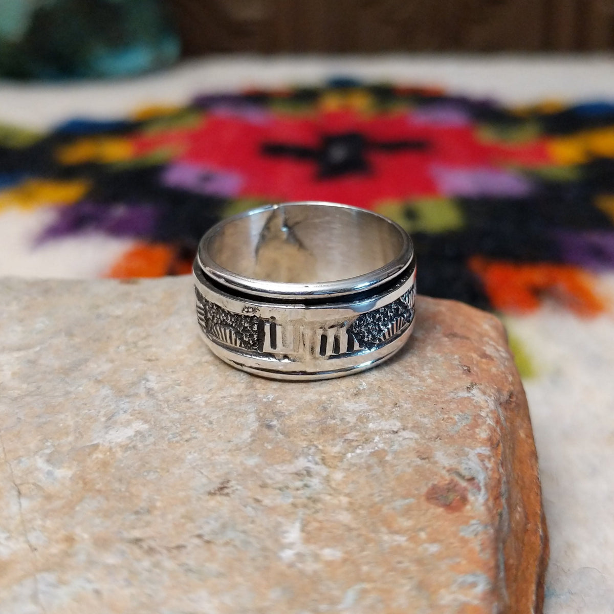 Silver spinner ring by Elaine Becenti with stamped geometric designs and layered movable bands.