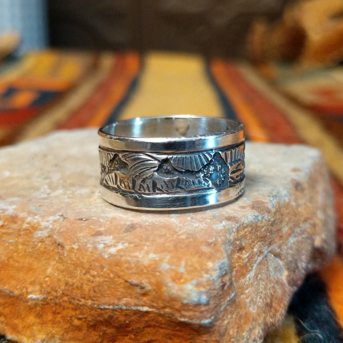 Silver Storyteller Ring by Elaine Becenti featuring a wide silver band with detailed landscape motifs, textured mountain designs, oxidized accents, and polished edges.
