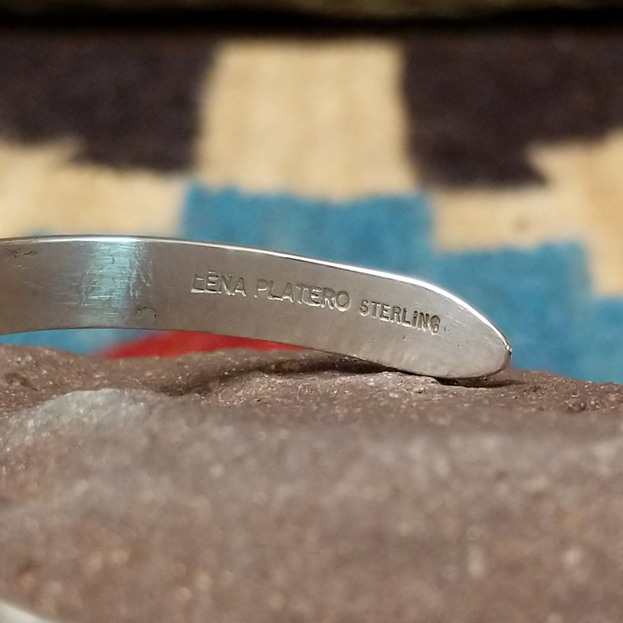 Slender silver feather cuff by Lena Platero, featuring a finely engraved sterling silver feather design in a handcrafted slim open cuff with polished finish. Artisan and Sterling Silver stamp.