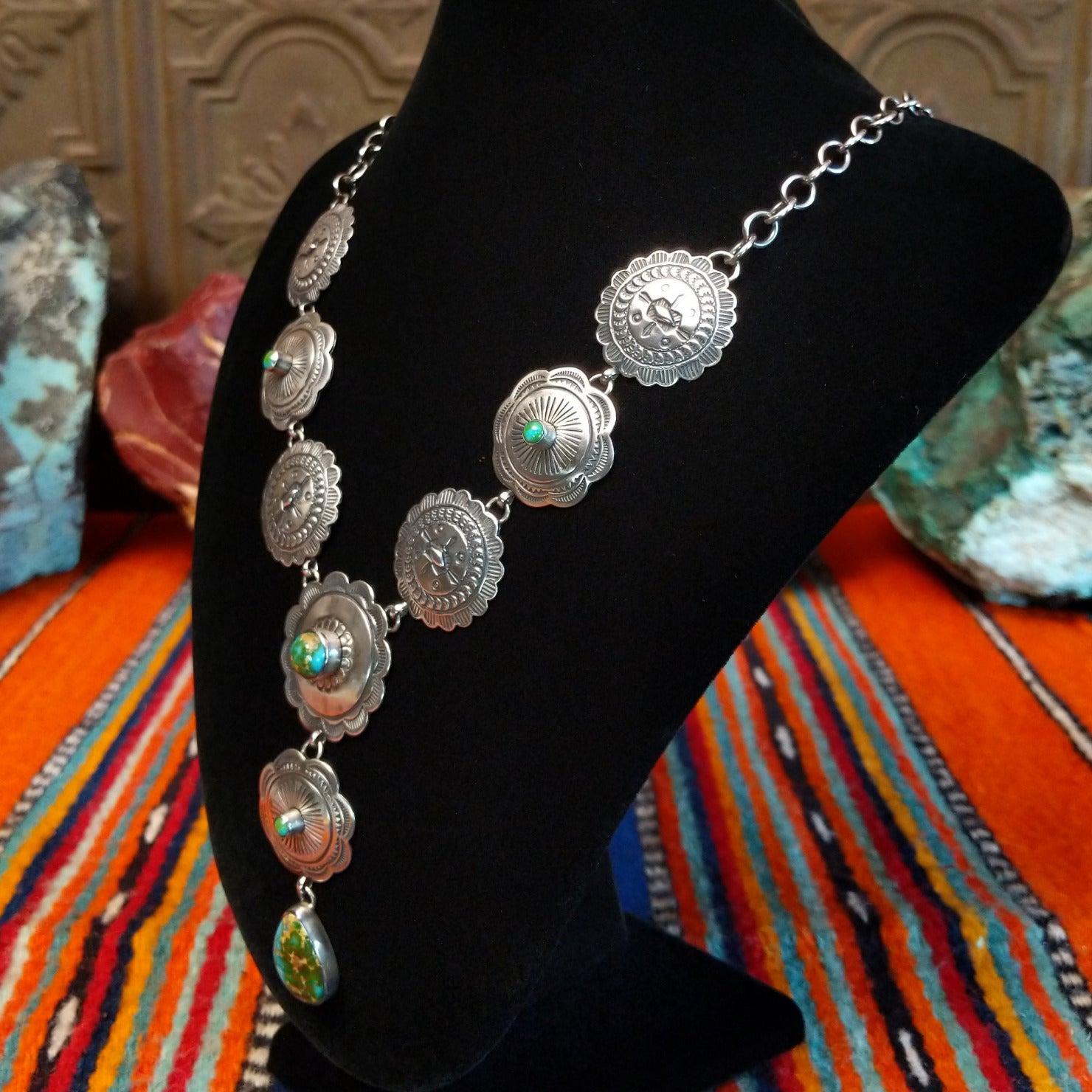 Small Sonoran Gold turquoise set in bezels that are atop the intricately decorated conchos with singural teardrop pendant.