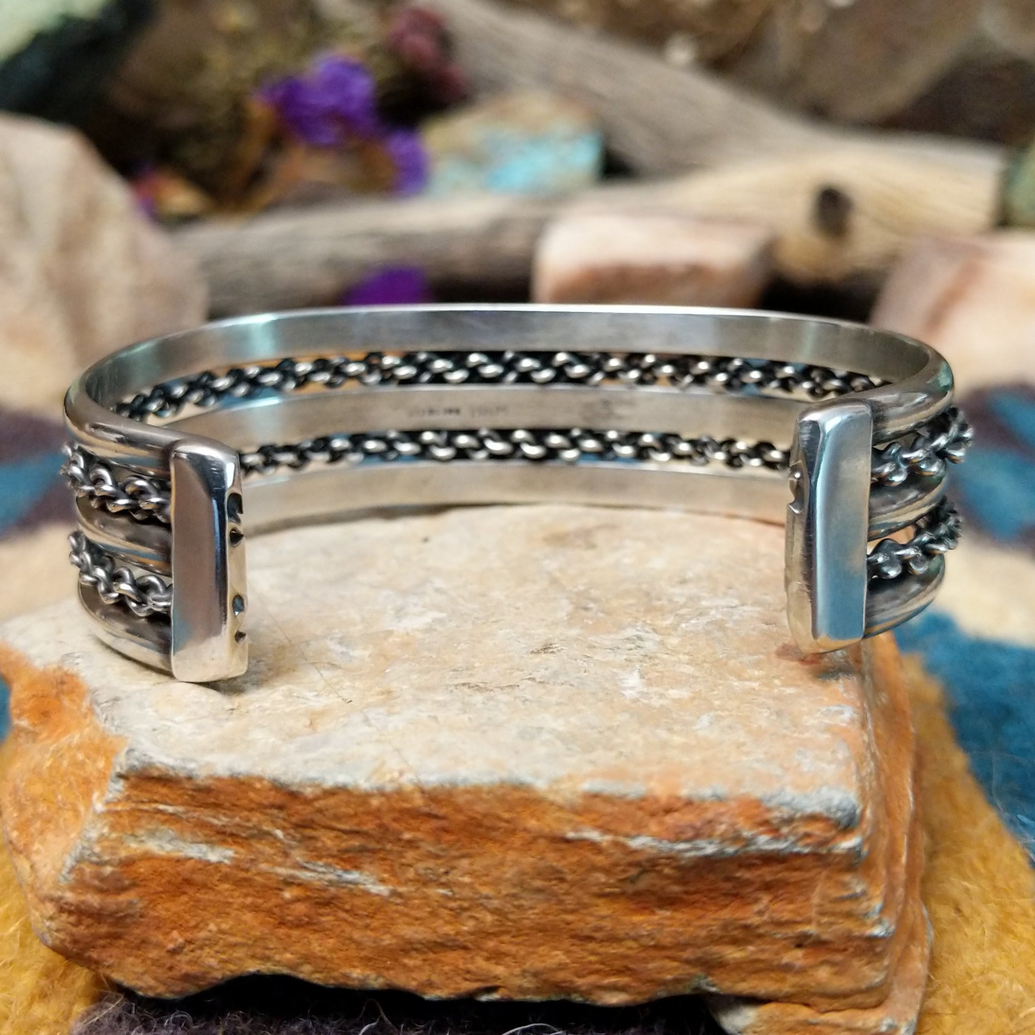 Handcrafted sterling silver cuff by H.R.M. featuring an oval Sonoran Gold turquoise cabochon centered between polished silver bands with dual oxidized chain accents; underside view.