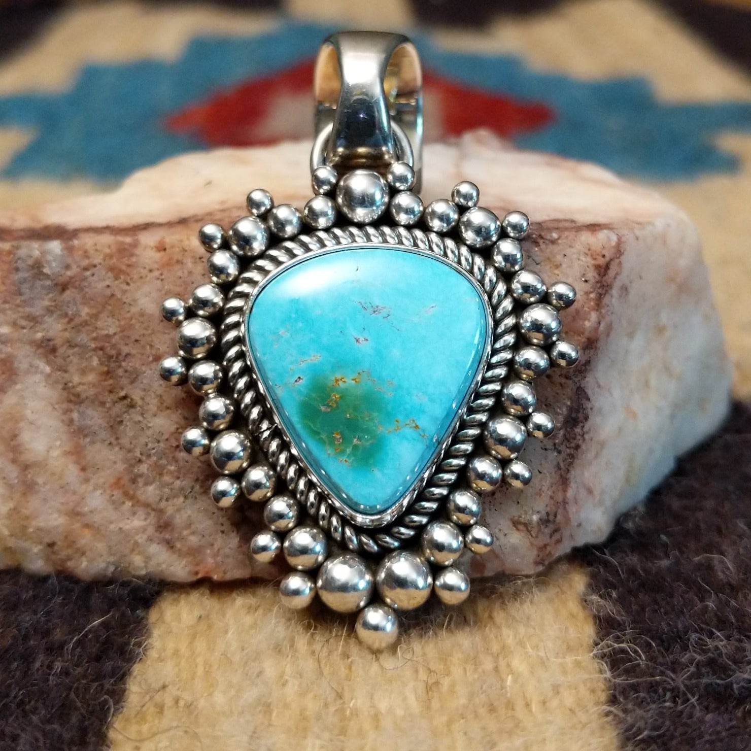 Sterling silver pendant featuring Sonoran Gold turquoise with green-blue tones and natural matrix, accented by dotted silver beadwork and handcrafted by Navajo artist Artie Yellowhorse. Front view.