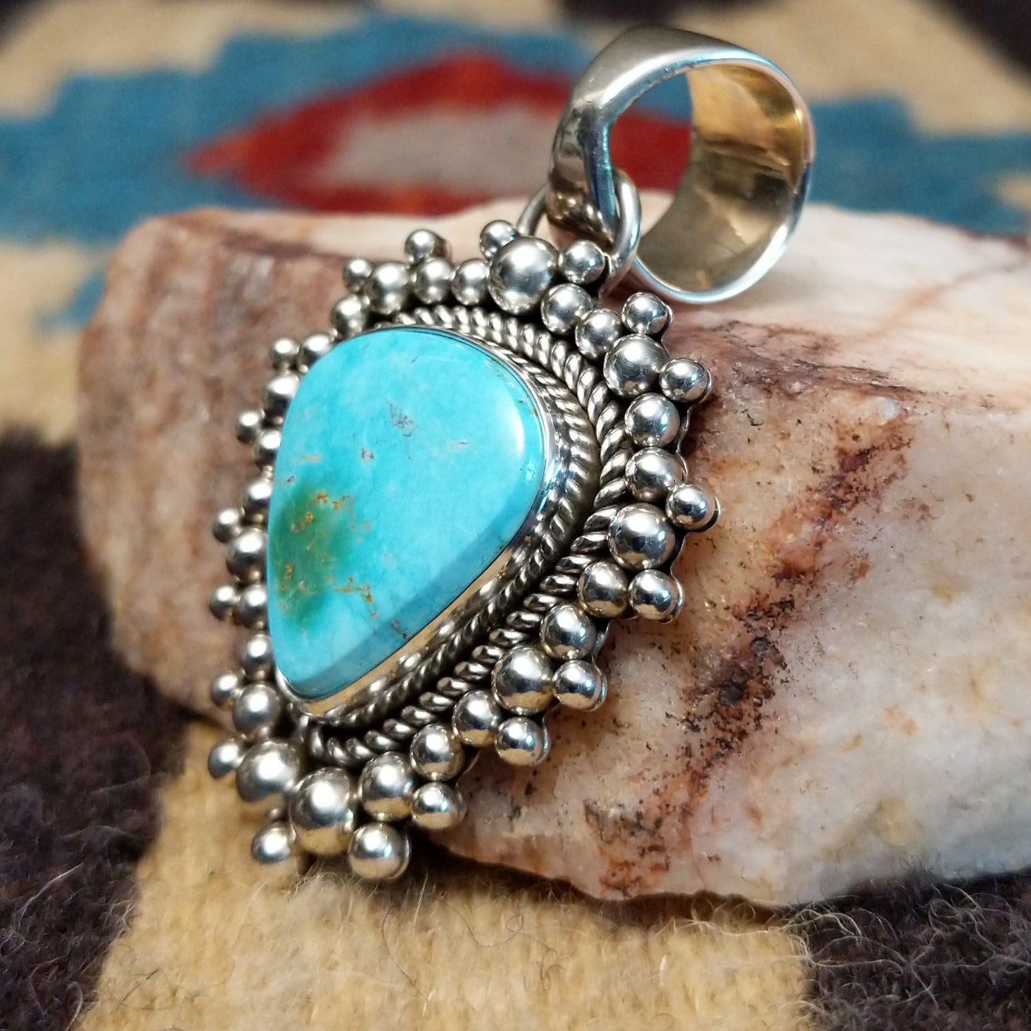 Sterling silver pendant featuring Sonoran Gold turquoise with green-blue tones and natural matrix, accented by dotted silver beadwork and handcrafted by Navajo artist Artie Yellowhorse. Side view.