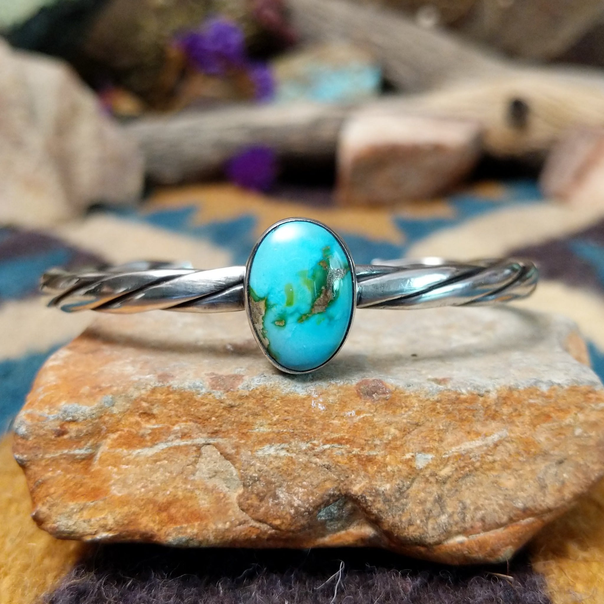 Handcrafted sterling silver twisted cuff by Raymond Coriz featuring an oval Sonoran Gold turquoise cabochon with vibrant blue, green, and natural golden matrix.