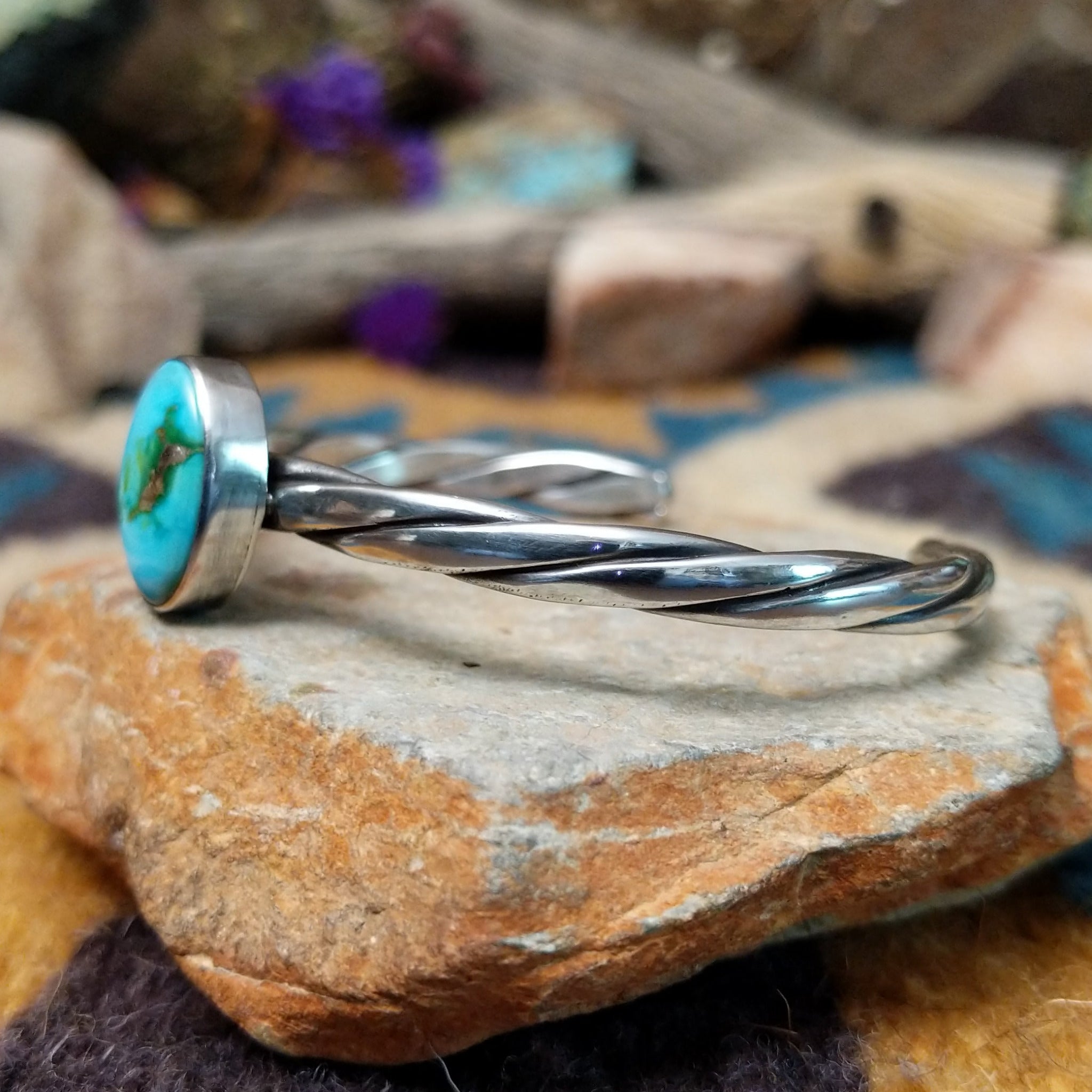Handcrafted sterling silver twisted cuff by Raymond Coriz featuring an oval Sonoran Gold turquoise cabochon with vibrant blue, green, and natural golden matrix; side view.