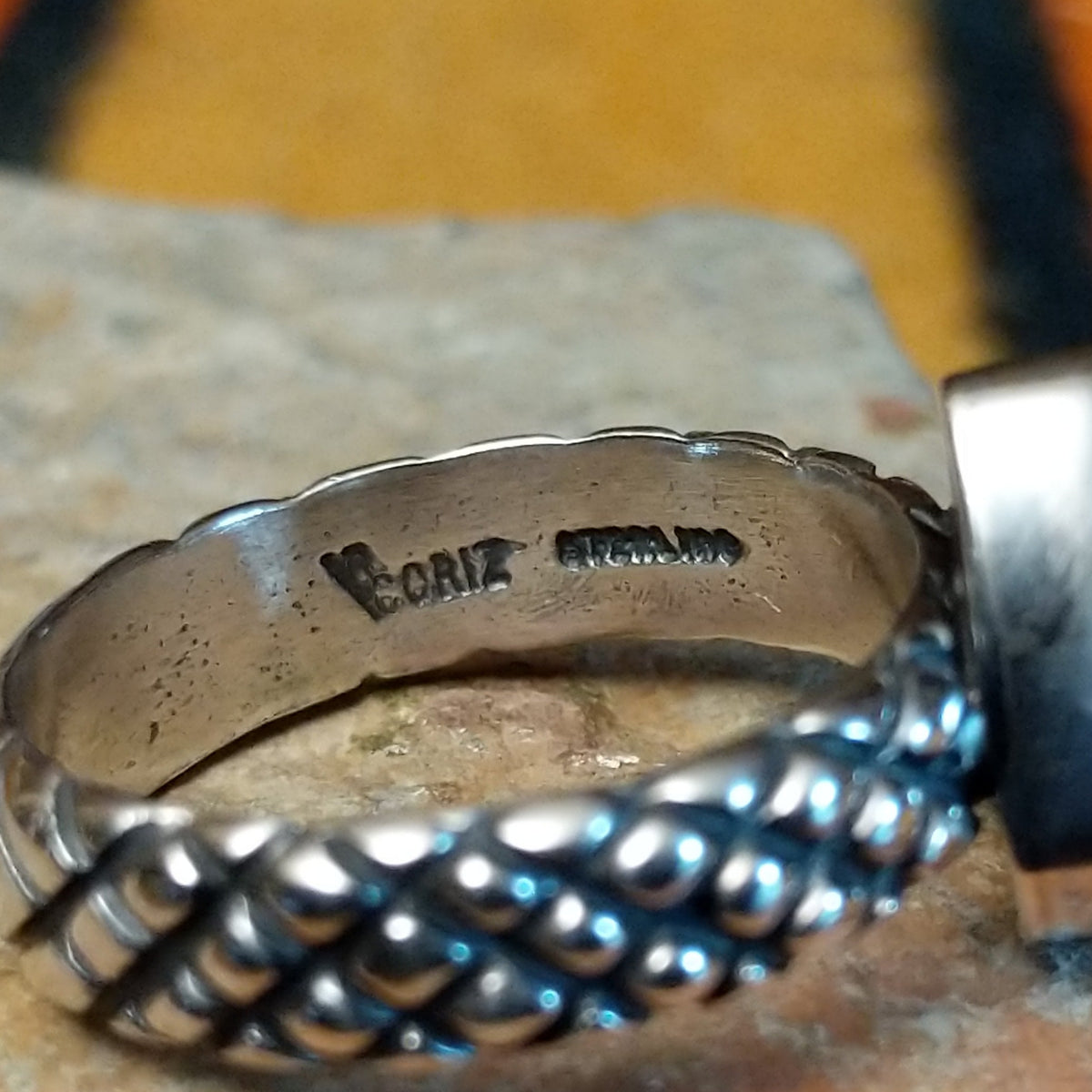 Sonoran Gold Turquoise Ring by Raymond Coriz featuring a pear-shaped green turquoise stone with natural matrix, set in sterling silver with a smooth bezel and decorative braided band; artisan and Sterling Silver stamp.