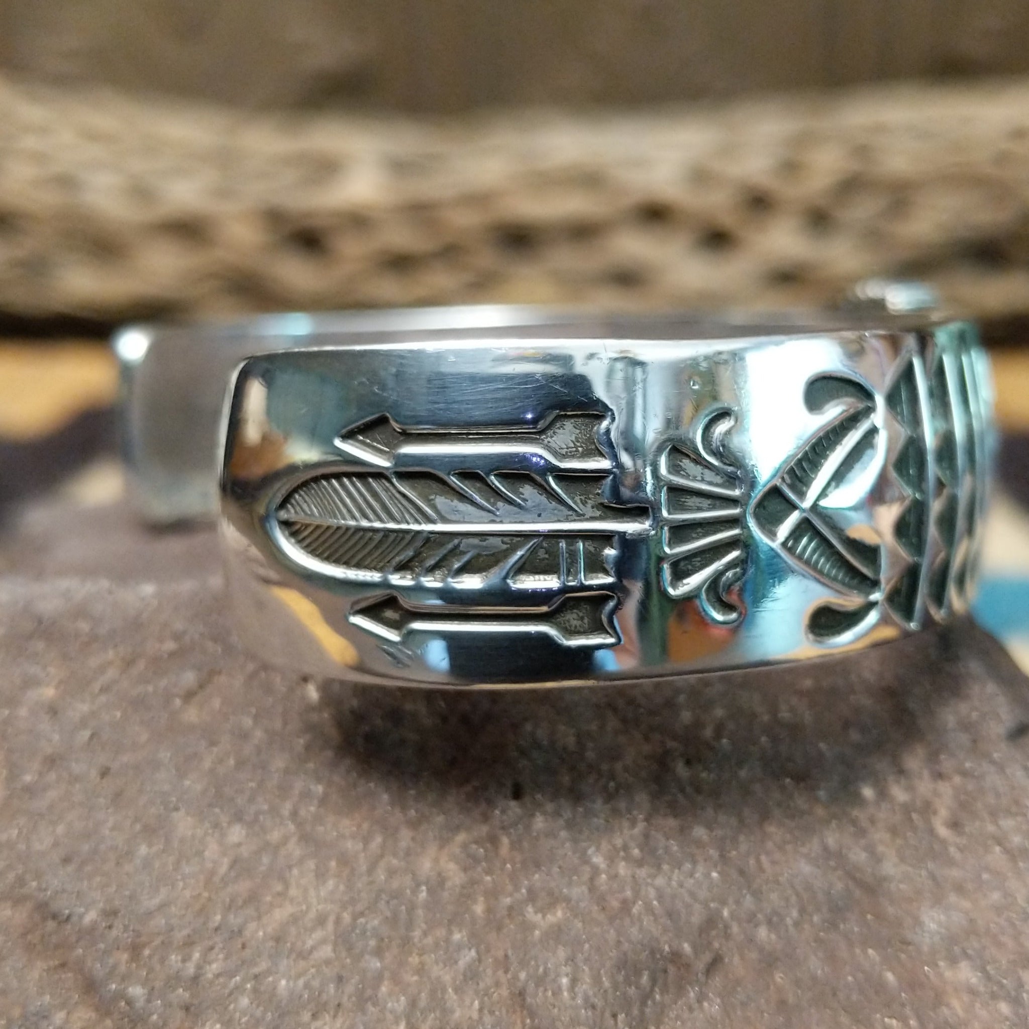 Sonoran Mountain turquoise cuff by Rydel Victor Curtis, featuring an oval blue Sonoran Mountain turquoise stone with natural golden-brown matrix set in a handcrafted sterling silver cuff with intricate geometric stampwork; side view.