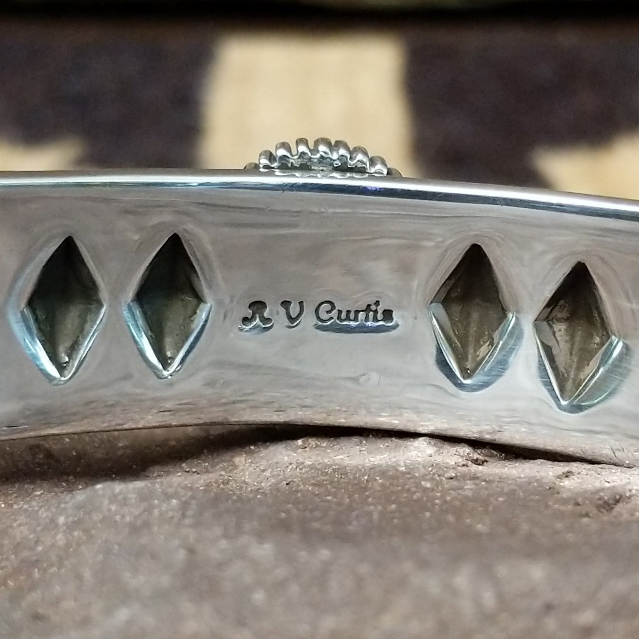 Sonoran Mountain turquoise cuff by Rydel Victor Curtis, featuring an oval blue Sonoran Mountain turquoise stone with natural golden-brown matrix set in a handcrafted sterling silver cuff with intricate geometric stampwork; artisan and Sterling Silver stamp.