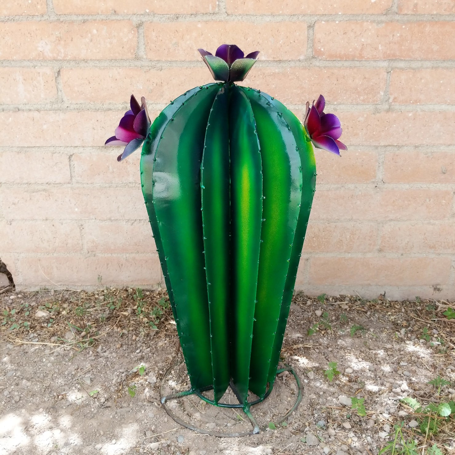A large metal saguaro sculpture, featuring purple blooms.