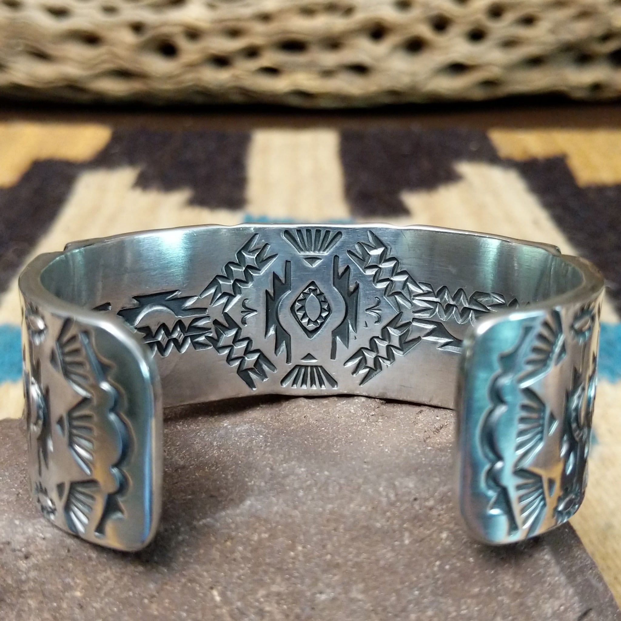 Spiderweb #8 turquoise cuff by Andrew Gordon, featuring an oval blue Spiderweb #8 turquoise stone with natural spiderweb matrix set in a handcrafted sterling silver cuff with hand-stamped fan and geometric designs; underside detail view.