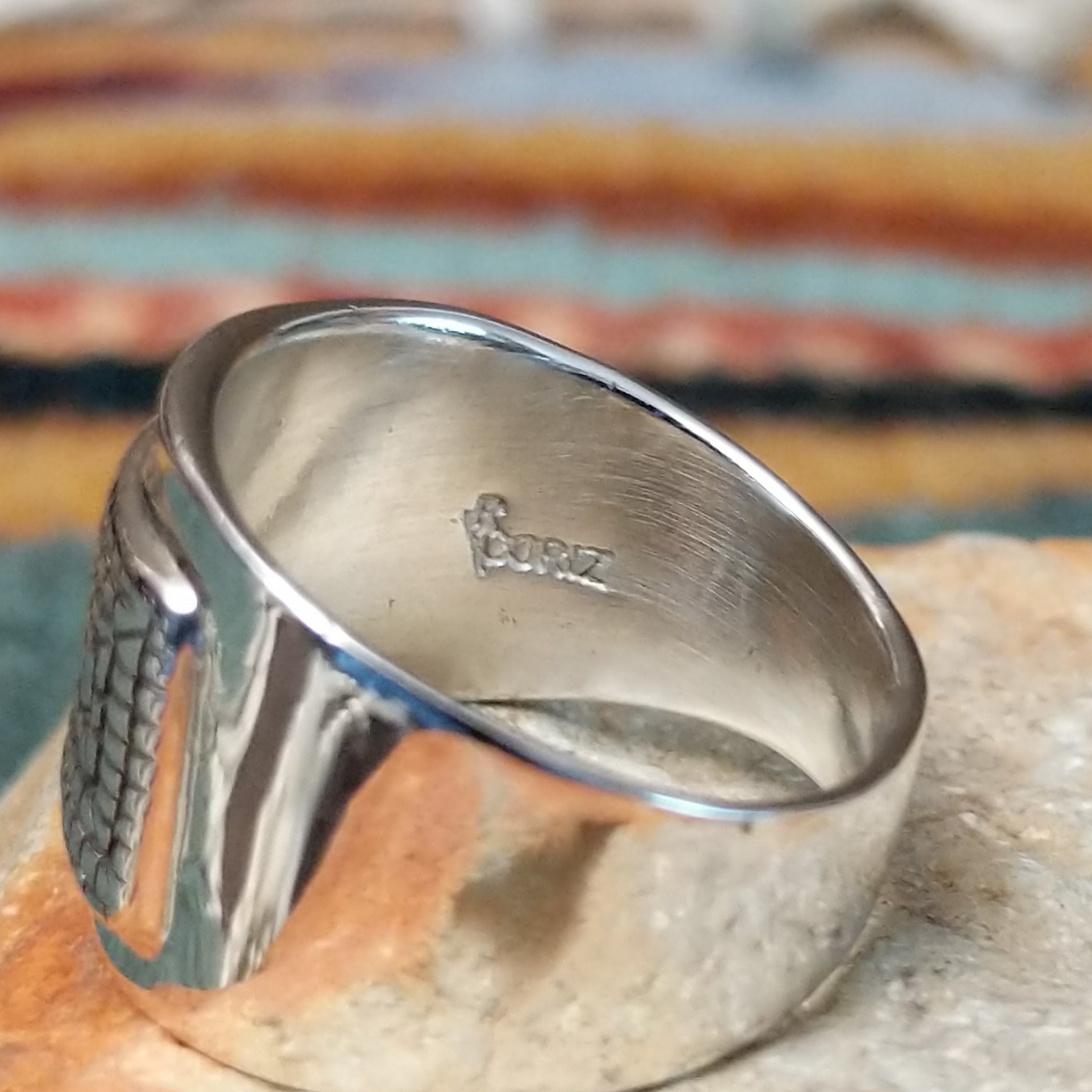 Handcrafted sterling silver ring by Raymond Coriz featuring an intricate rectangular spiral design with stamped details, an oxidized background, and a wide polished silver band; artisan stamp.