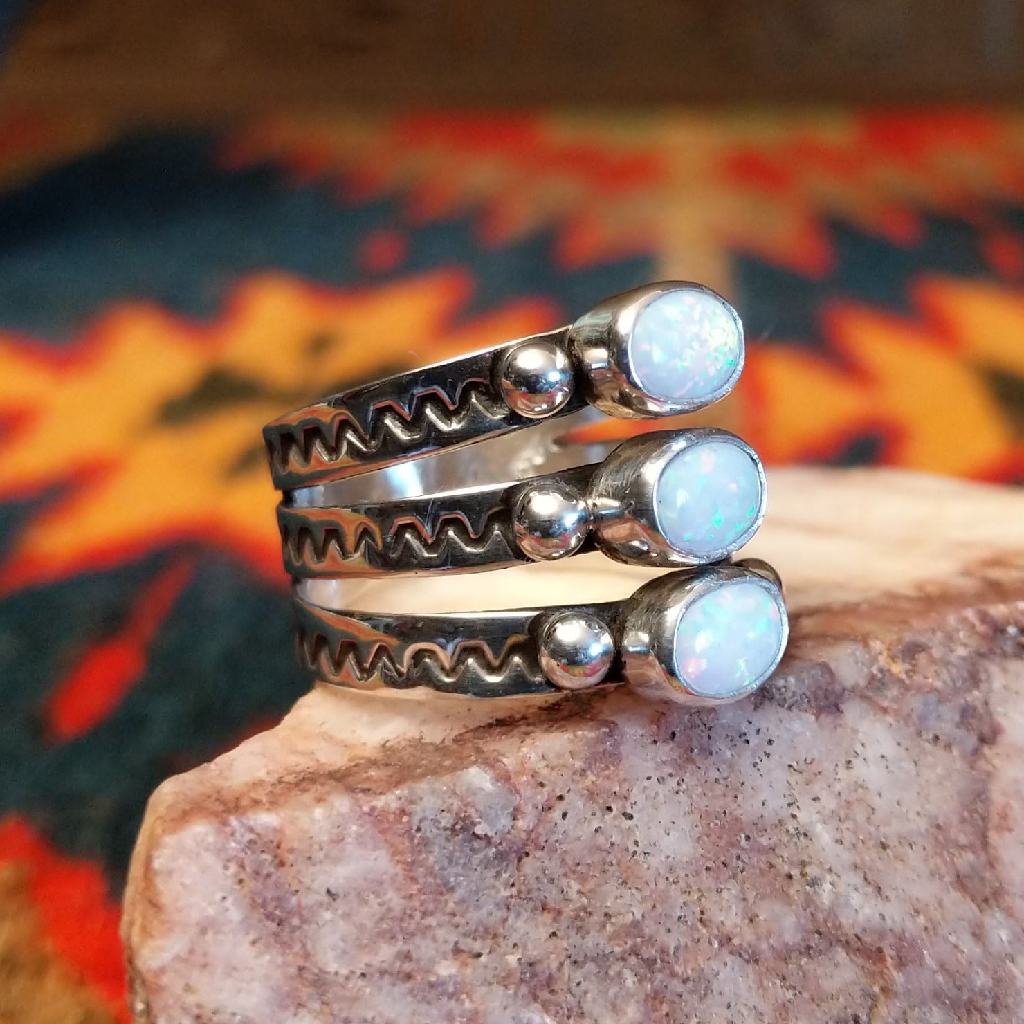 Stacked sterling silver ring with manmade opal set in oval bezels, featuring stamped patterns on the band.