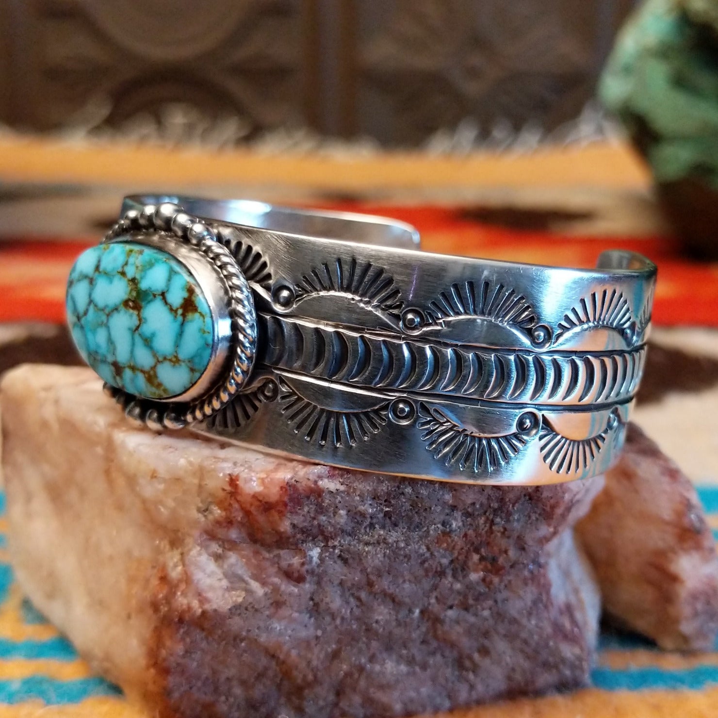 Sterling silver cuff bracelet with Kingman turquoise set in the oval bezel, framed by twisted rope, dotted accents, and stamped designs on the band.