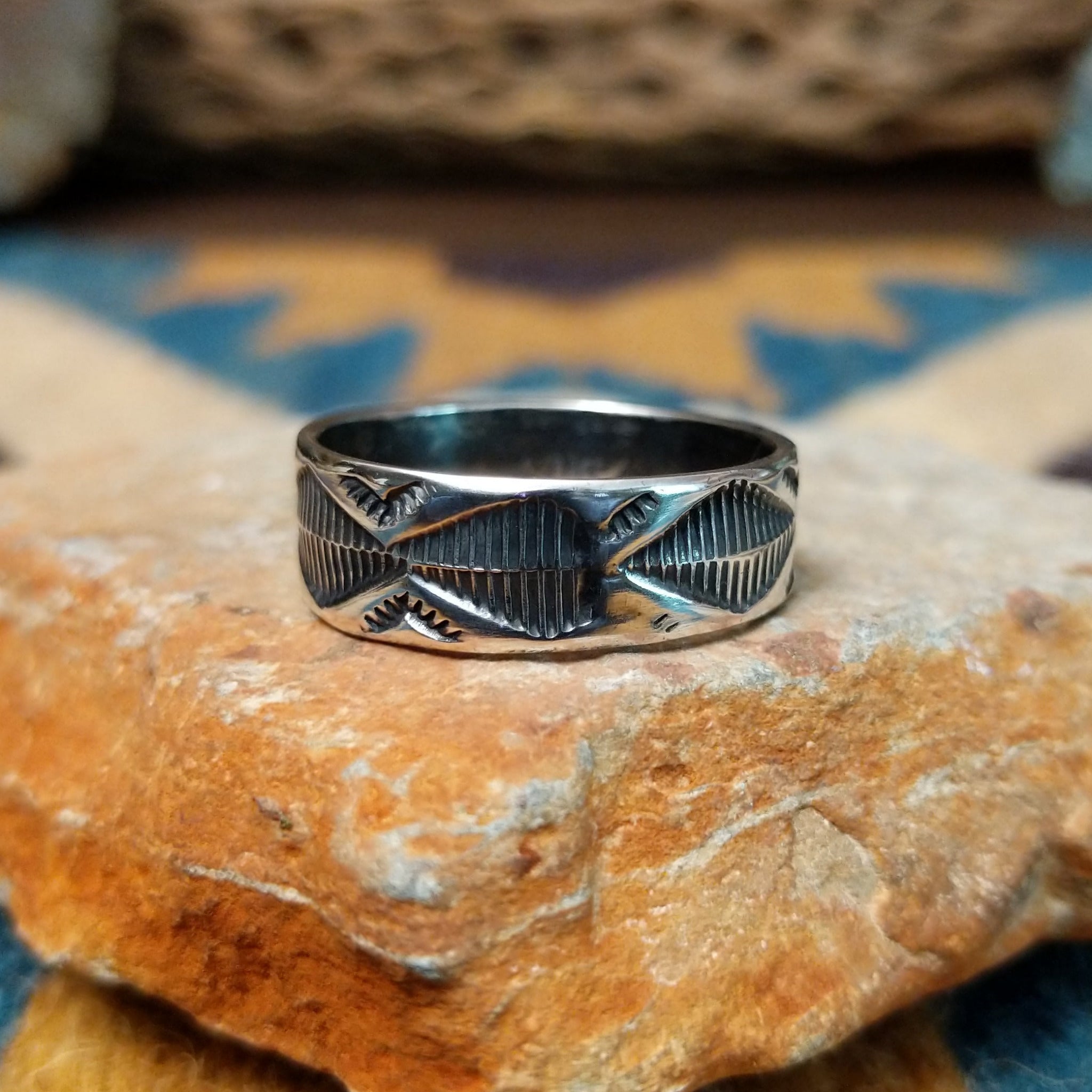 Handcrafted Navajo sterling silver stamped ring by Travis Teller featuring a wide band with deep traditional geometric stampwork and an oxidized finish.