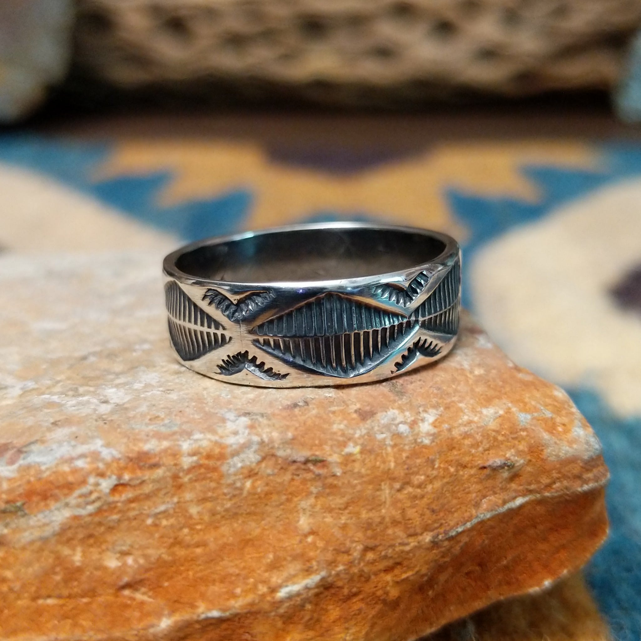 Handcrafted Navajo sterling silver stamped ring by Travis Teller featuring a wide band with deep traditional geometric stampwork and an oxidized finish.
