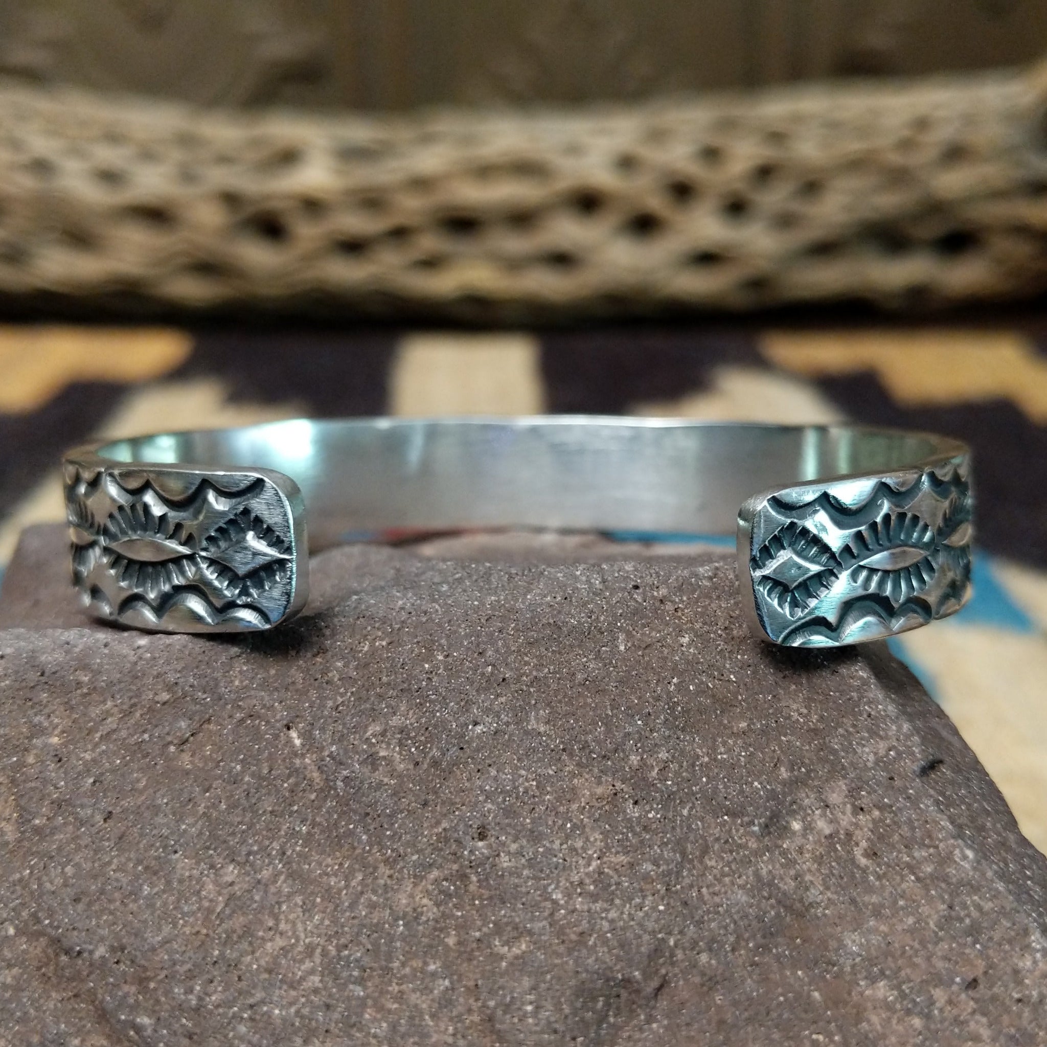 Stamped sterling silver cuff by B. Shorty, featuring intricate hand-stamped geometric and floral-inspired patterns on a handcrafted open sterling silver cuff. Underside view.