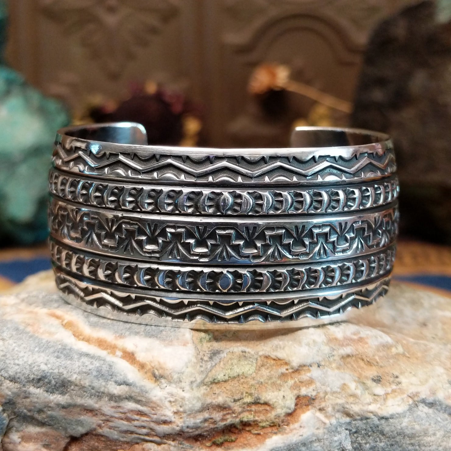 Wide sterling silver cuff bracelet with hand-stamped geometric and crescent motifs.
