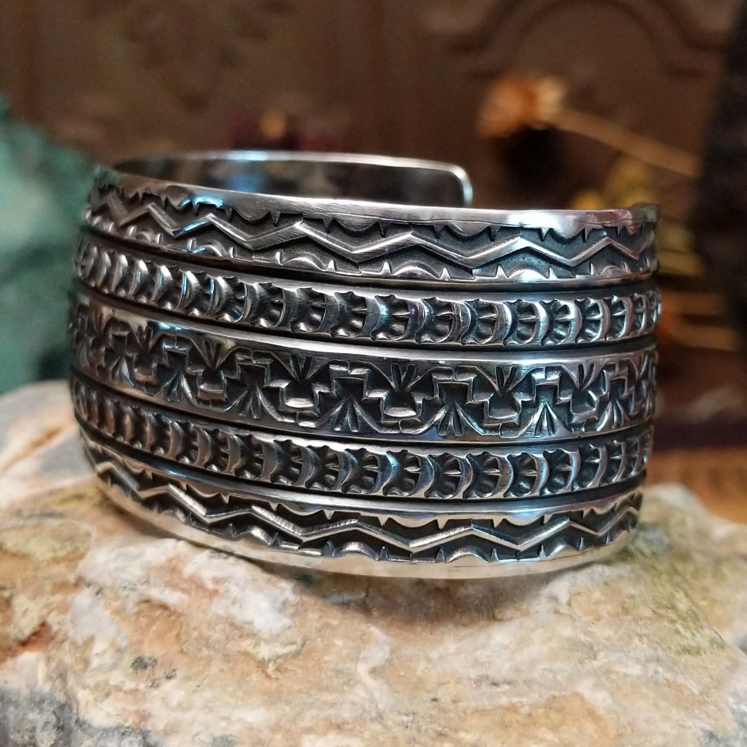 Wide sterling silver cuff bracelet with hand-stamped geometric and crescent motifs.